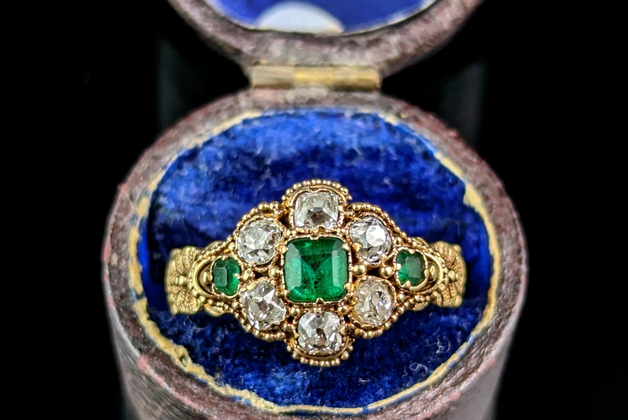 This antique Emerald and Diamond cluster ring is a true showstopper and exudes regal beauty and luxury.

This impeccable ring is crafted in rich buttery 18ct gold with a lightly bevelled band and the most beautiful ornate shoulders, the shoulders