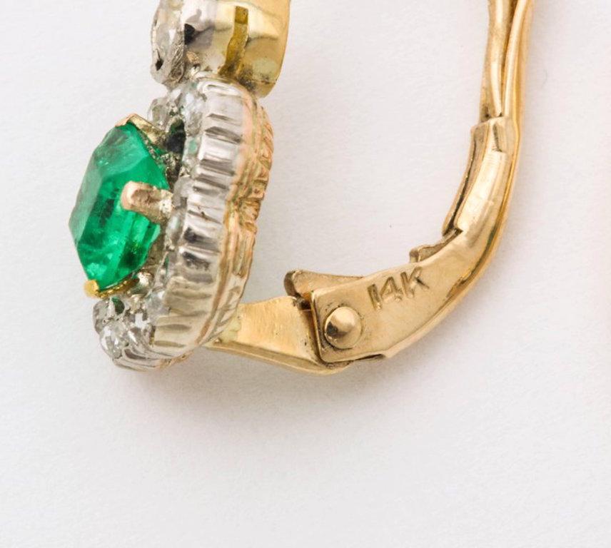 A delicate pair of natural Colombian square cut emeralds surrounded by old mine-cut  diamonds and suspended from bezel set round diamonds in 18K gold with lever closures.