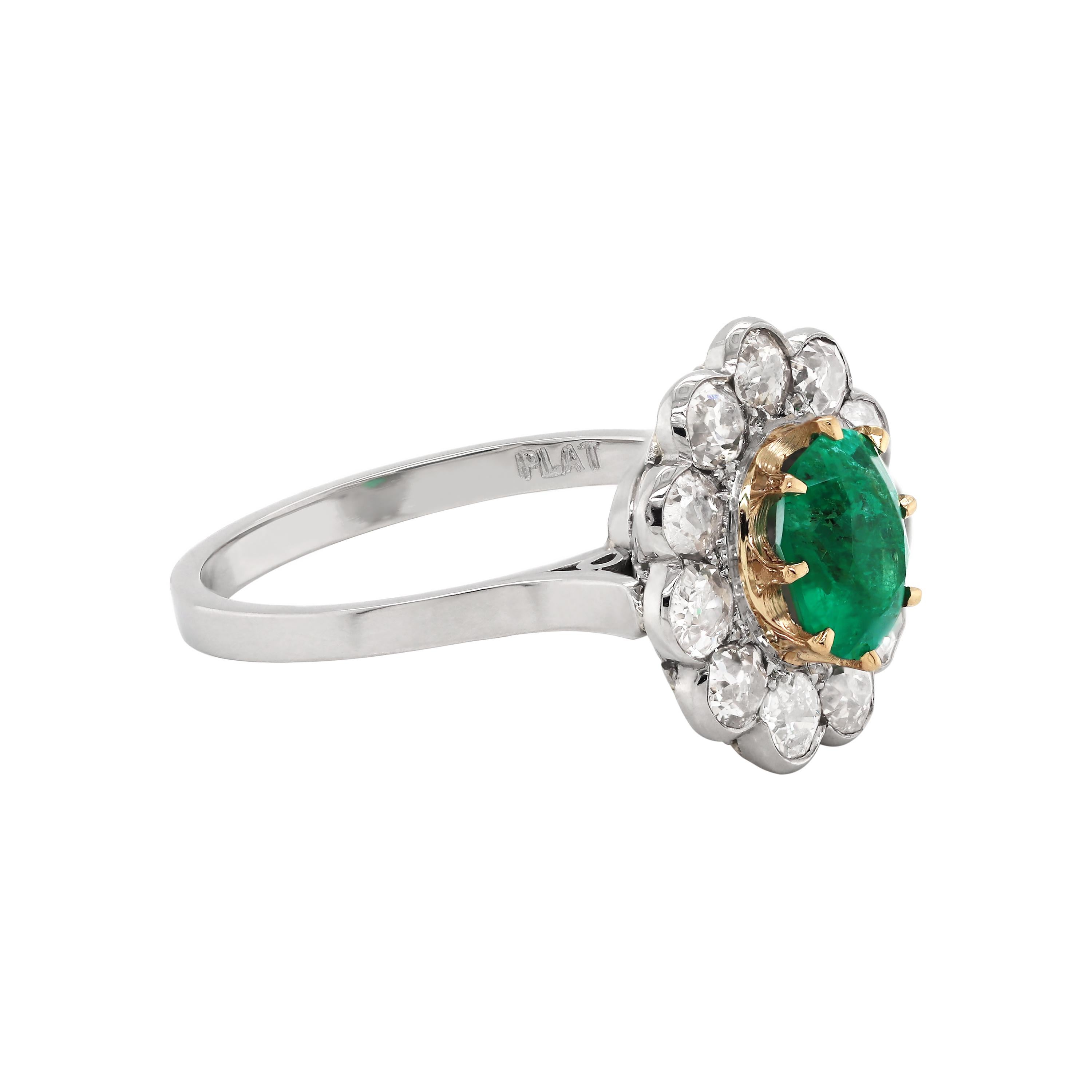 This beautiful hand made emerald and diamond coronet cluster ring features an oval shaped emerald in the centre, mounted in an open back, 18ct yellow gold claw setting, with an approximate weight of 1.00 carat. The emerald is surrounded by eleven