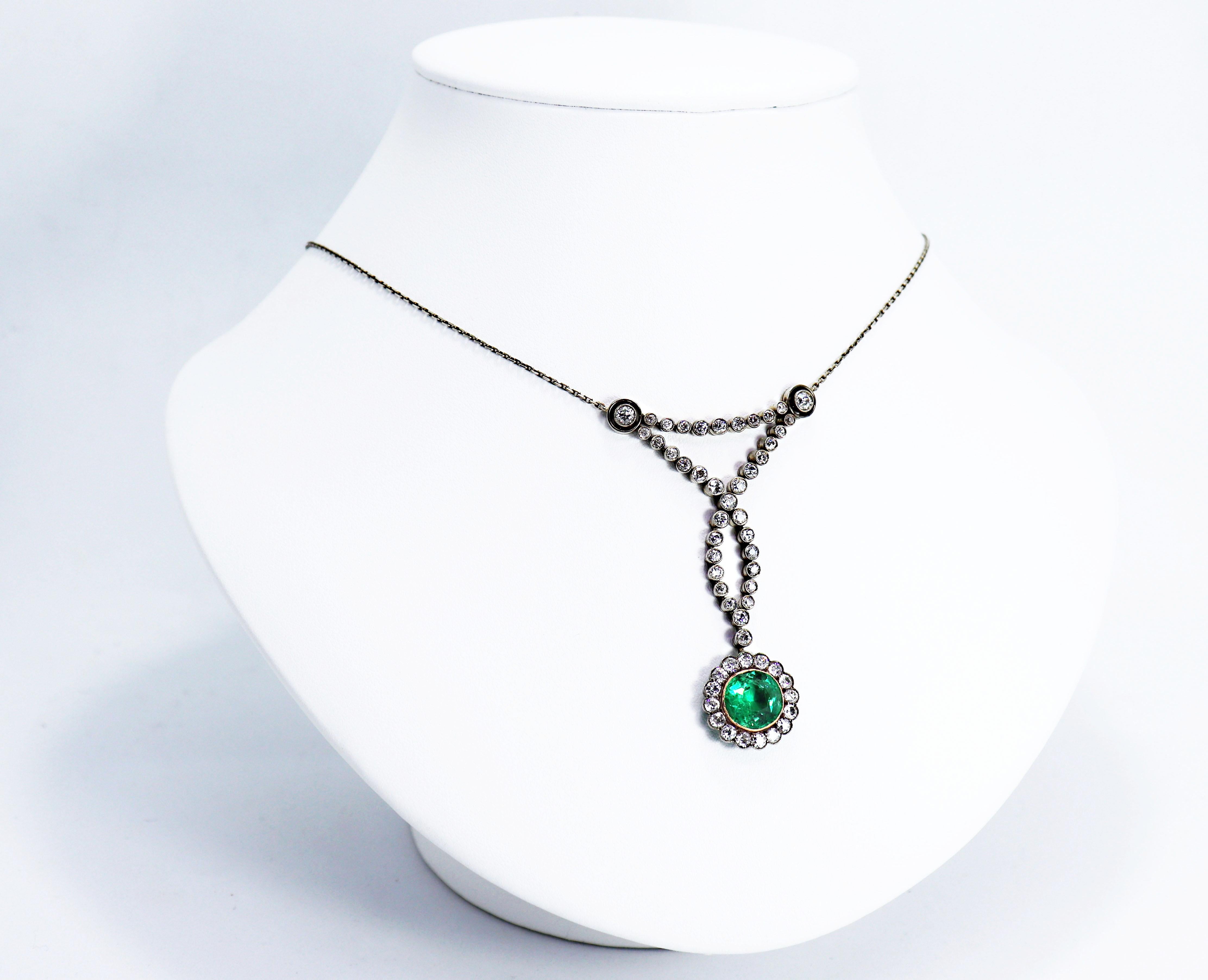Magnificent antique necklace set with a round shaped emerald weighing approximately 3.00+ carats accompanied by 54 old mine cut diamonds in rub over, open back settings weighing a total approximate weight of 3.10 carats in a beautifully elegant