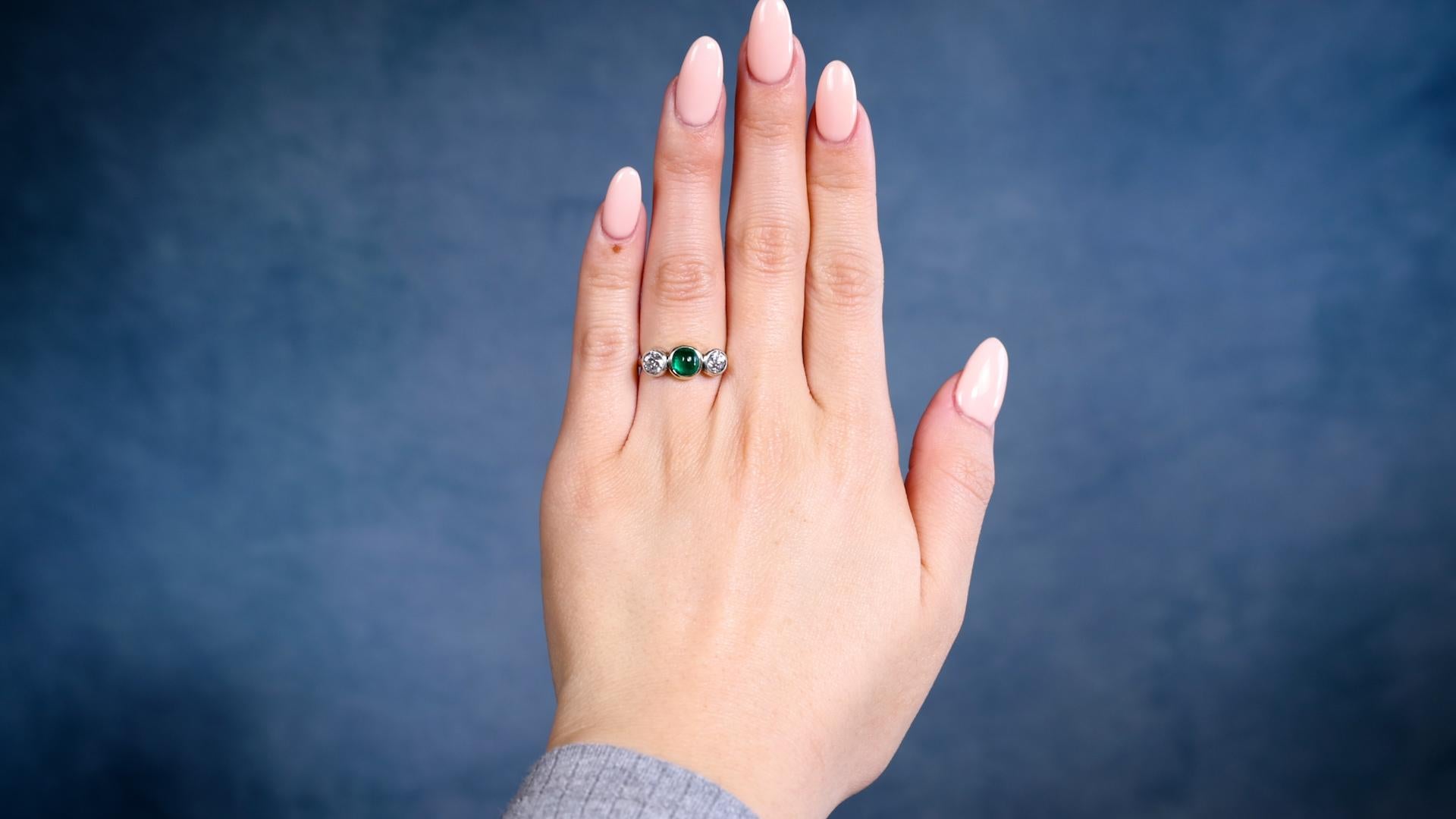 Ein antiker Smaragd Diamant 14k Gelbgold Silber Drei Stein Ring. Mit einem Smaragd im Cabochon-Schliff mit einem Gewicht von etwa 0.90 Karat. Akzentuiert durch zwei alte Diamanten im europäischen Schliff mit einem Gesamtgewicht von ca. 0,90 Karat,