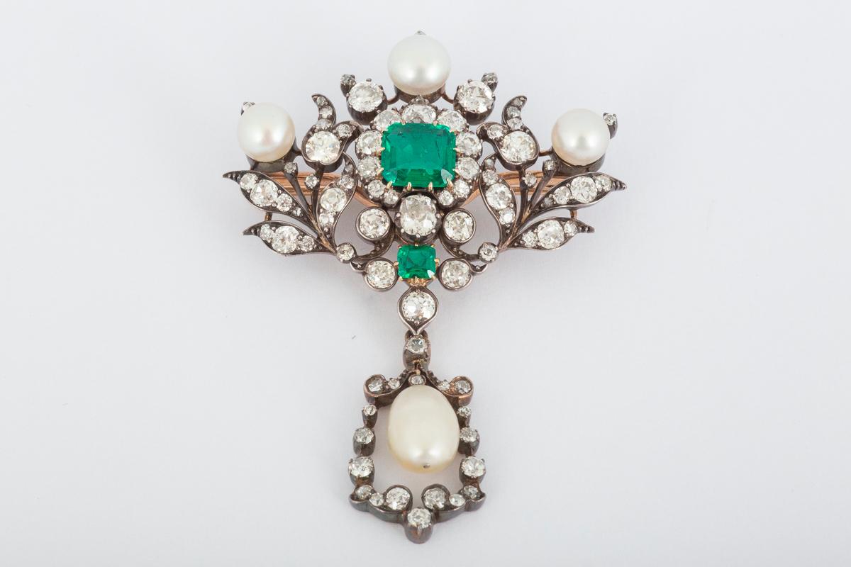 A fine, quality made antique floral brooch from the mid Victorian period which can also be worn as a pendant. The central Columbian emerald of approximately 2 carats is surrounded by old brilliant cut diamonds and three natural (oriental) pearls.