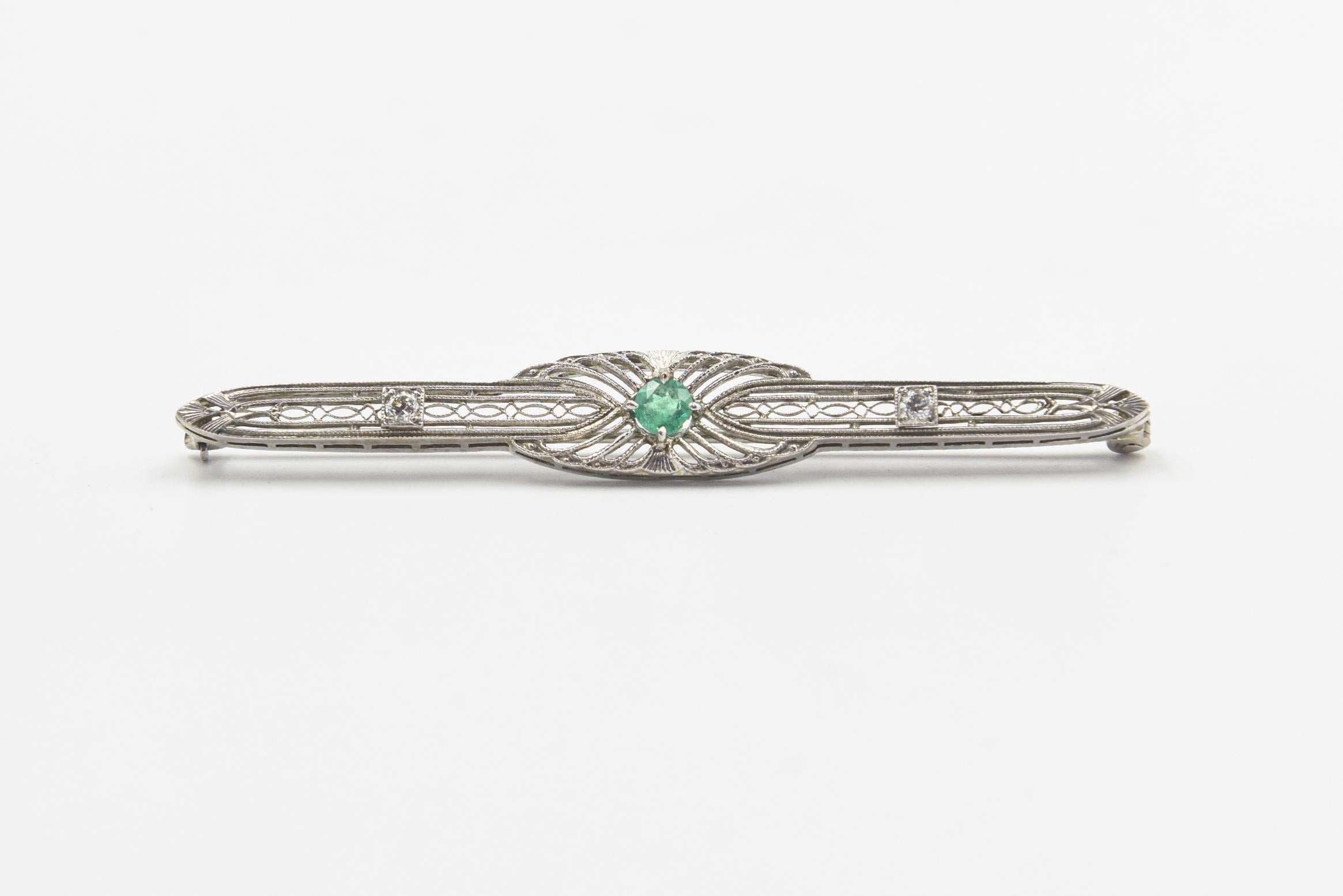 Early 20th Century antique bar brooch featuring a centrally set emerald in a 18k white gold filagree brooch with 2 round diamond accents.  The piece tested 18k with a metal testing gun. It has odd hallmarks that I do not recognize.