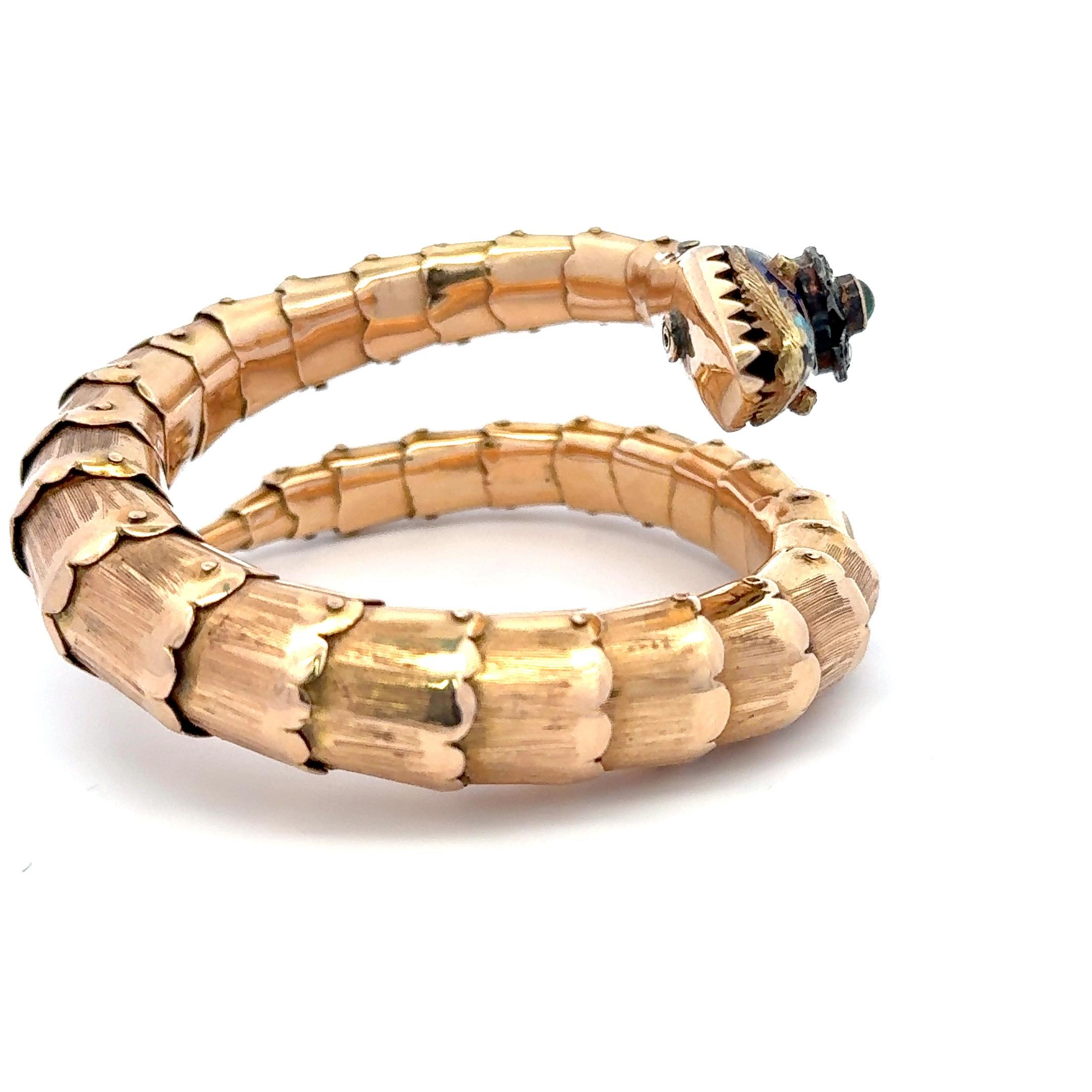 Antique snake wrap bracelet featuring a cabochon Emerald flanked with diamonds and colorful enamel weighing 45.1 grams in 18 karat yellow gold. 