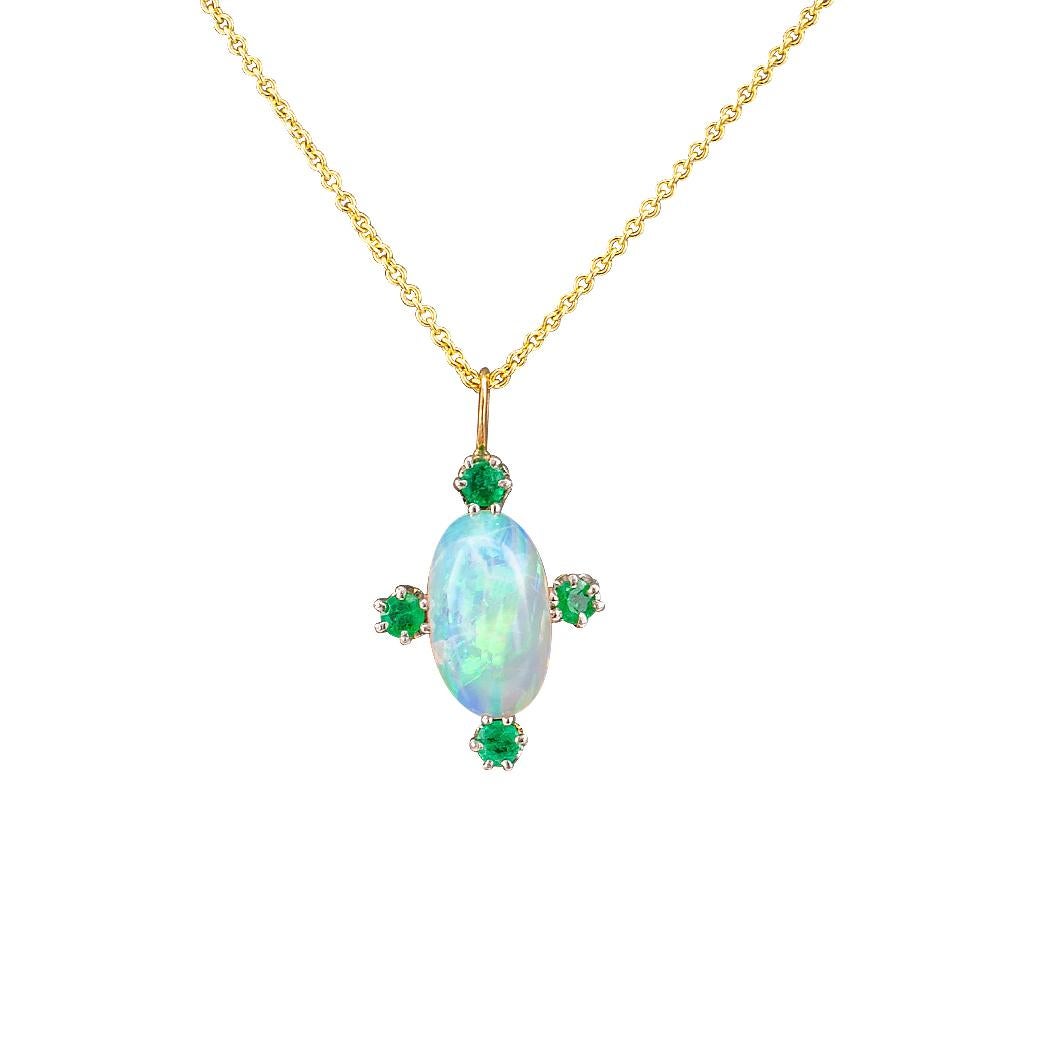 Antique emerald and opal gold and platinum pendant circa 1910. Showcasing and elongated oval opal, framed at the cardinal points by four small round emeralds, mounted in 14-karat gold and platinum, suspended from a delicate cable link chain. We love