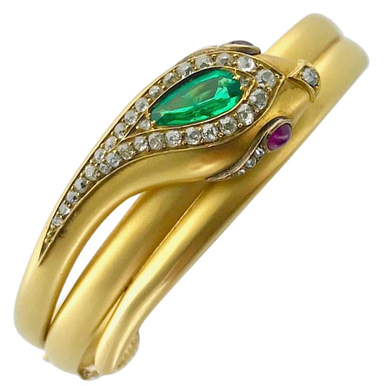 A Late 19th Century Emerald, Ruby and Diamond Bangle.
Modelled as a snake, the hinged bangle set with a pear-shaped emerald, with cabochon ruby eyes, the head accented by old brilliant-cut diamonds.
Circa 1890.
Inner circumference 6.50 inches.