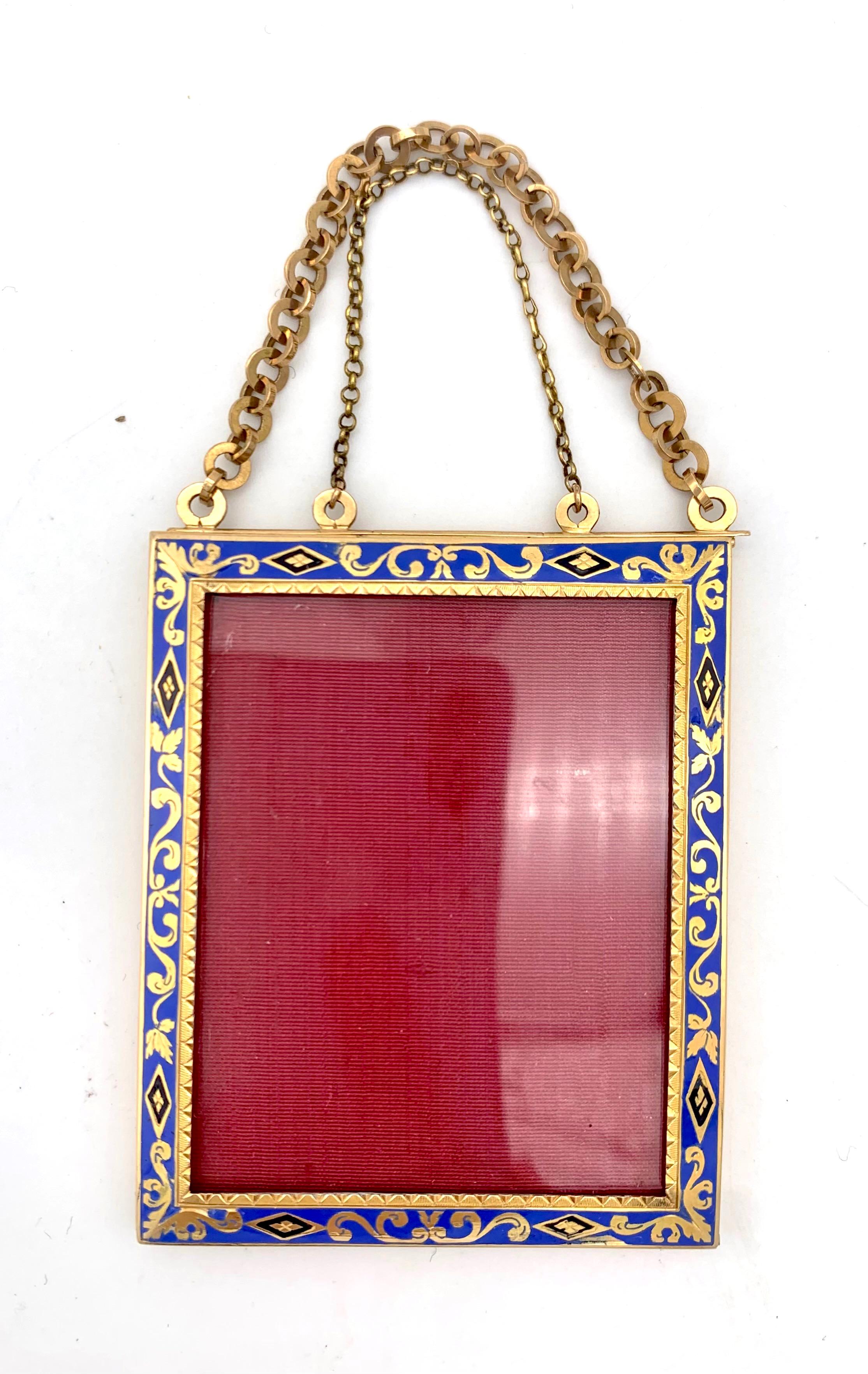 This gold and glass frame was created in the first decade the nineteenth century out of 18 karat gold. The frame is decorated with foliage and lozenges and blue and black enamel. It is suspended from two kinds of gold chains.  The inner border is