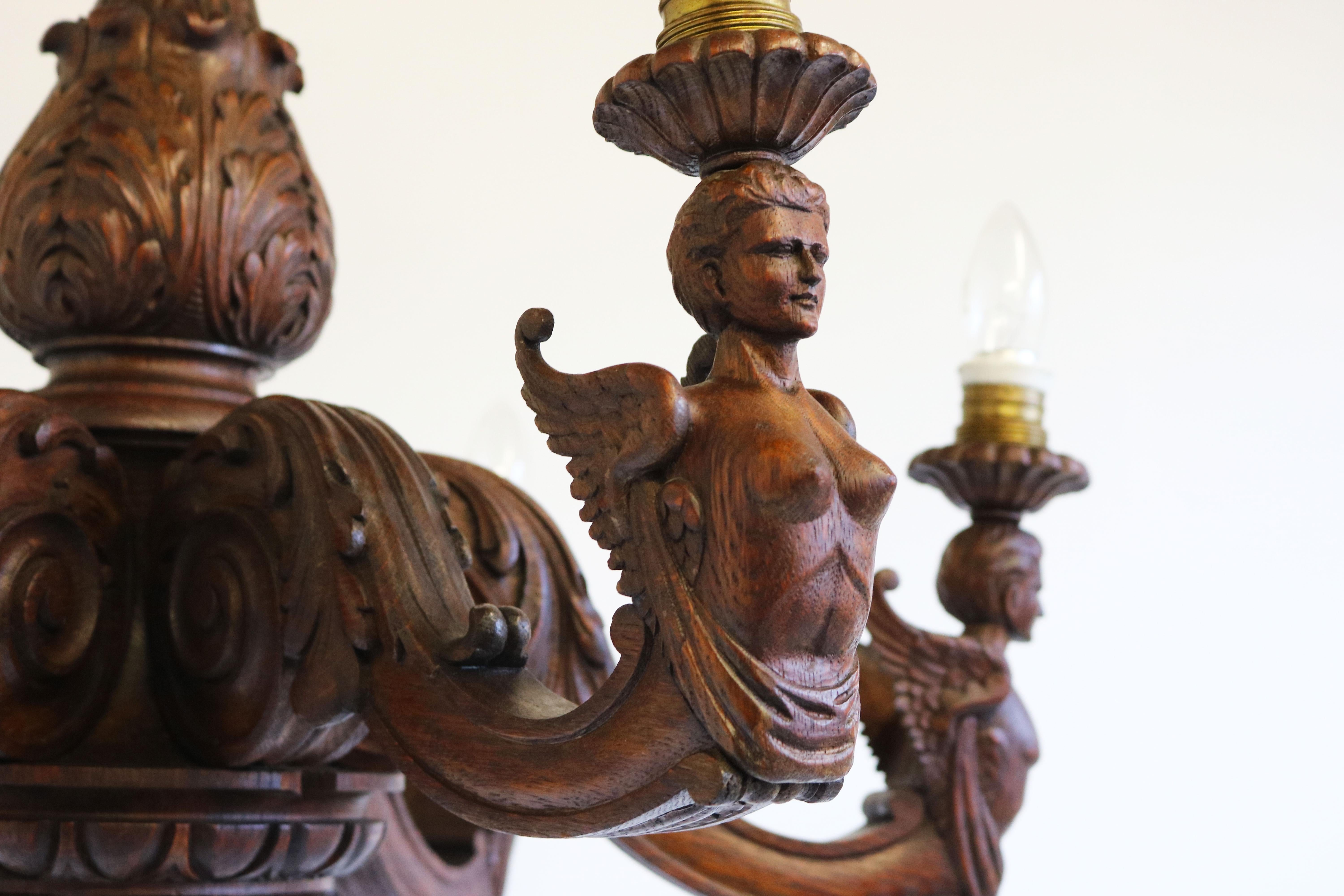 Simply amazing! This fully hand-carved Empire style chandelier in solid oak from France 19th century. 
The chandelier has 3 male figures & 3 female figures on its arms all displayed with wings. Gorgeously sculpted by a master carver fully in the