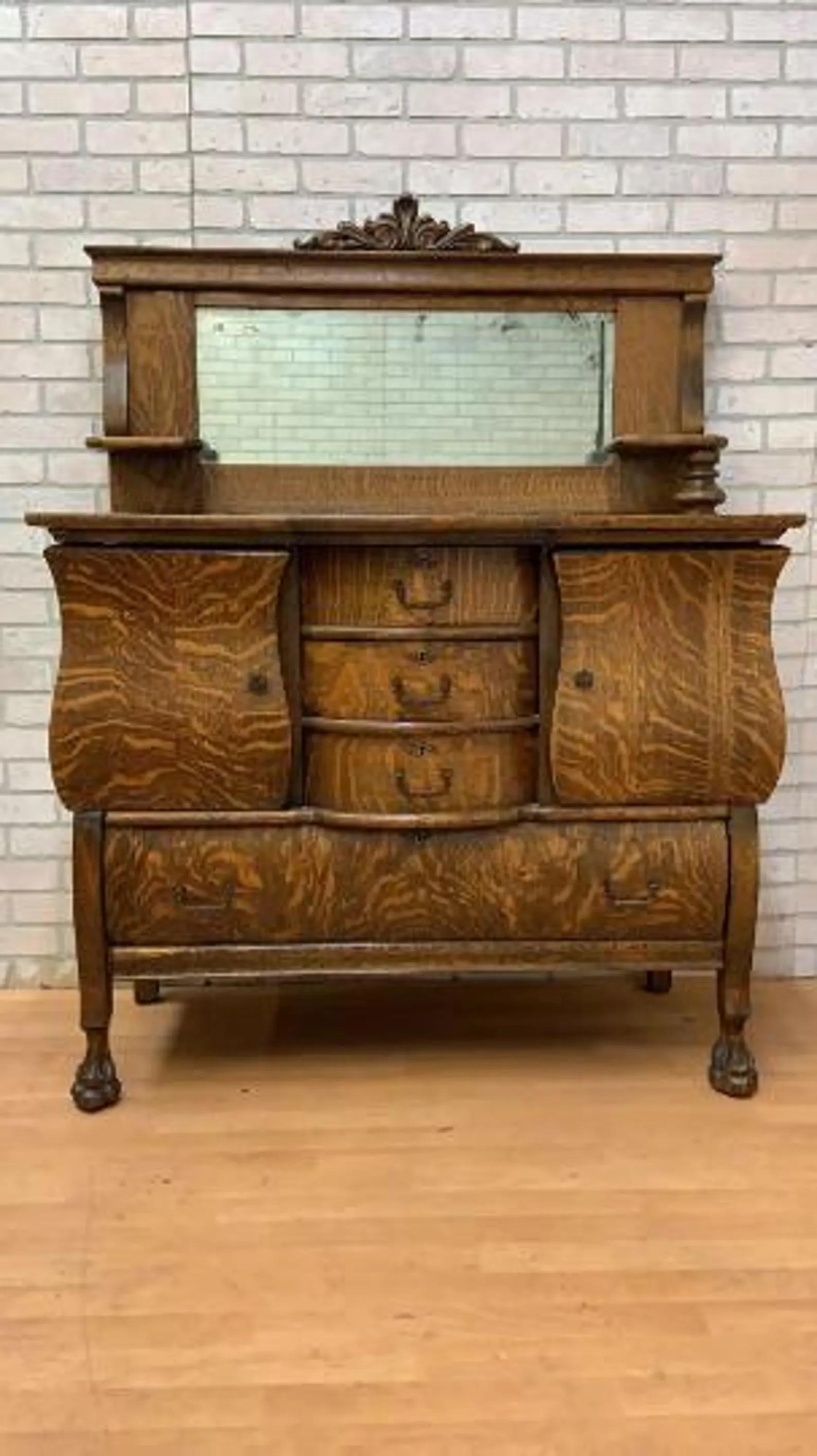 Antique Empire Antique Quarter Sawn Oak Buffet / Sideboard / Bar Cabinet with Mirror

This antique sideboard with a mirror top features a distinctive tiger oak wood grain. It features three small central drawers, one large drawer at the base, and
