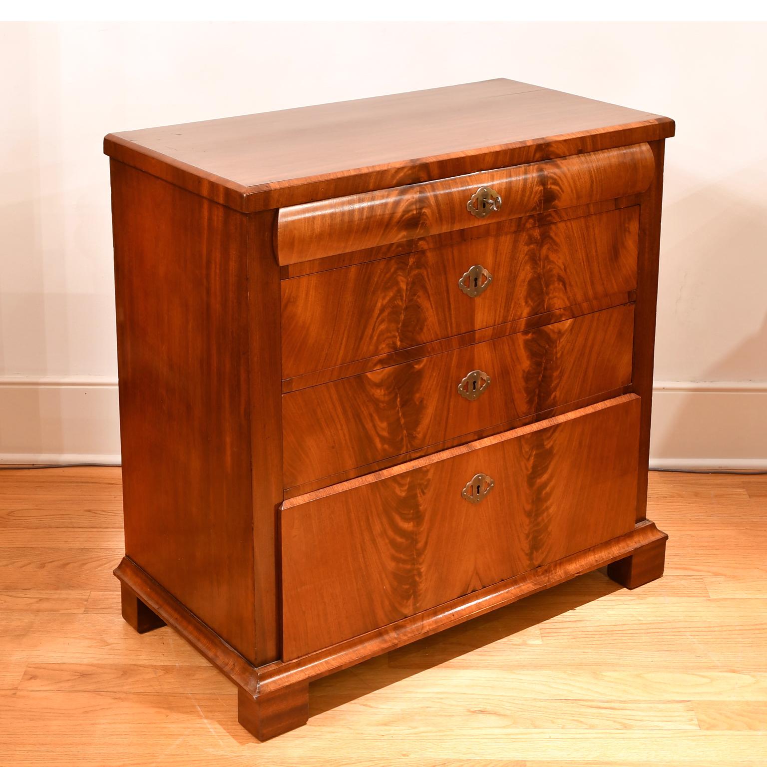 A handsome North German Biedermeier chest of drawers in West Indies mahogany whose fine figuring is expertly book-matched throughout highlighting the beauty of the wood and overall design. Chest offers four drawers of staggered depths and rests on