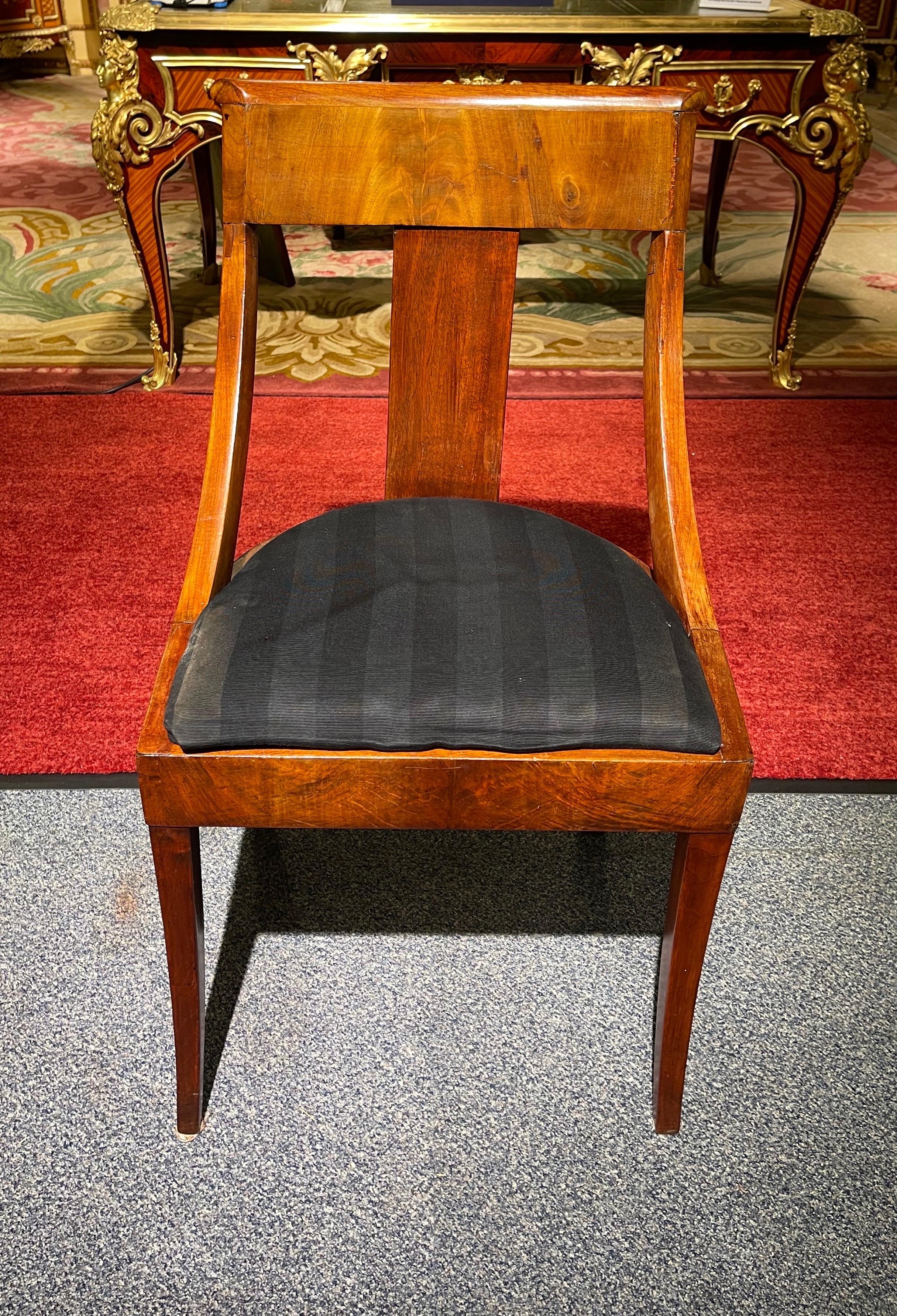 Antique Empire chairs from around 1900

Solid wood mahogany. Seat upholstered and covered with black fabric. Very stable and robust built. Hind legs in classic Empire saber shape. Timeless and classic design.