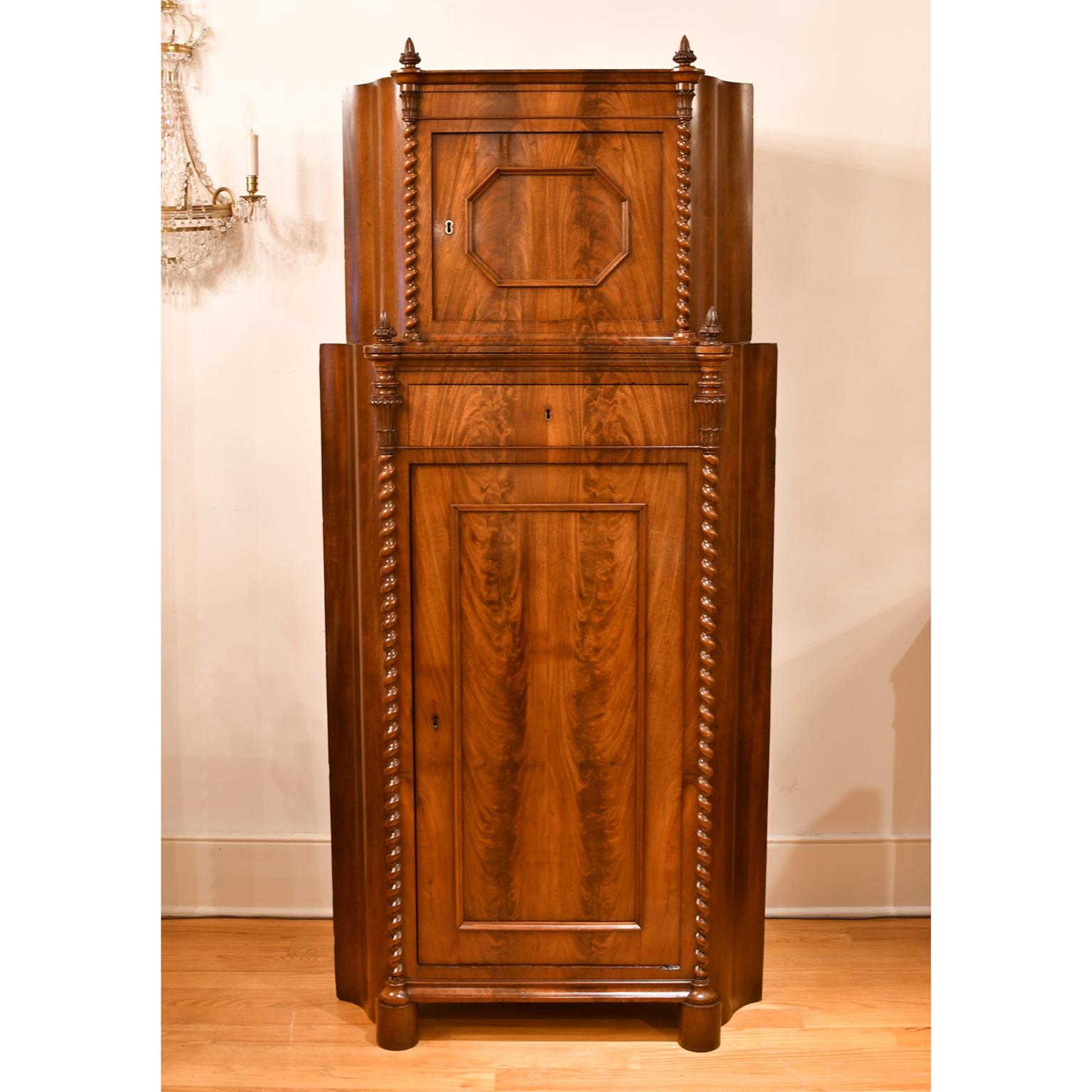 A very handsome Empire corner cupboard in Fine West Indies mahogany whose beautiful figuring is highlighted by the expert book-matching throughout. Features a smaller cabinet with octagonal-shaped panel on the top door, that rests over a larger