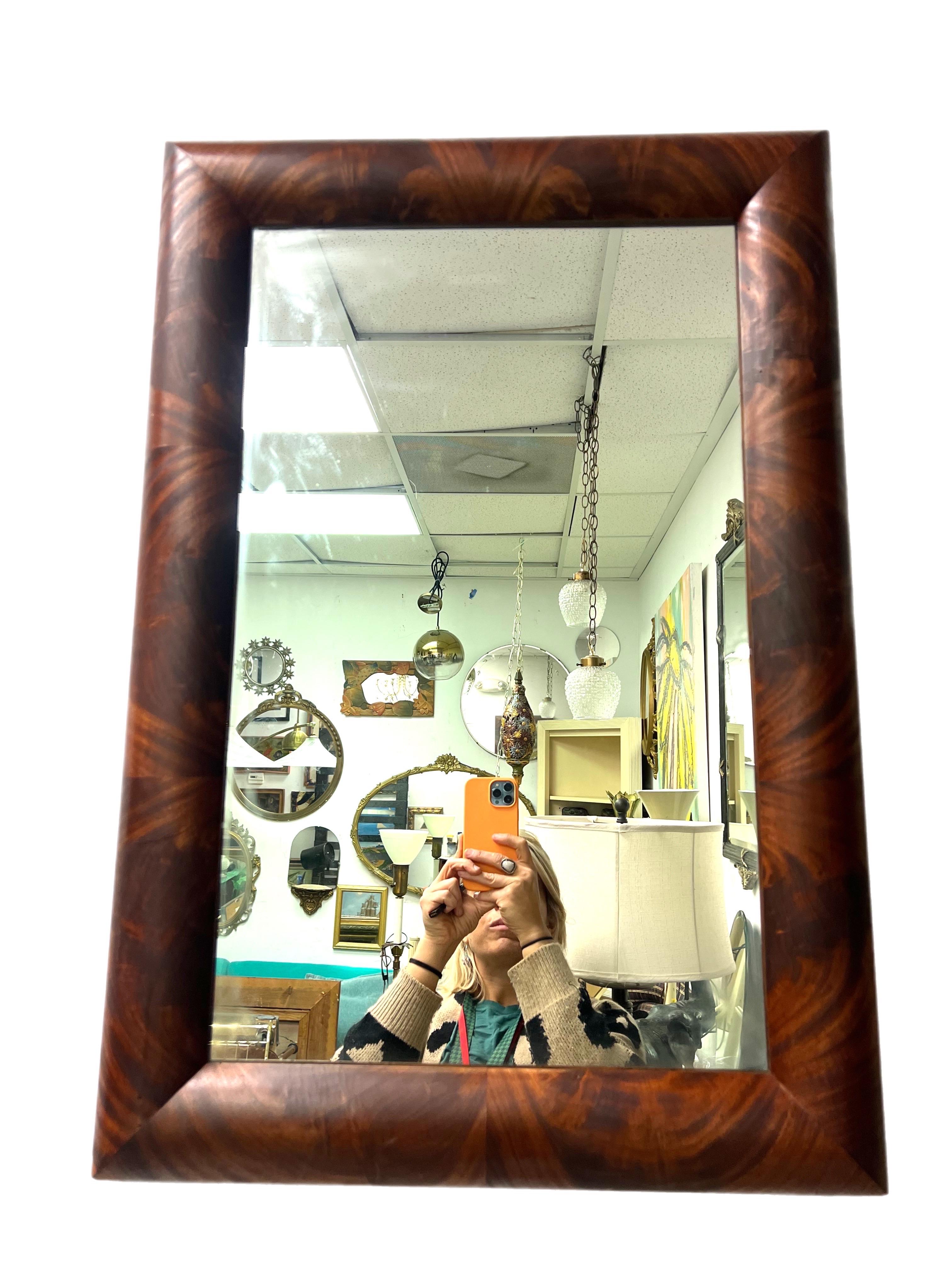 An absolutely stunning and handsome flame mahogany framed mirror. This would look great and add warmth and masculinity to any decor. Circa late 19th century.