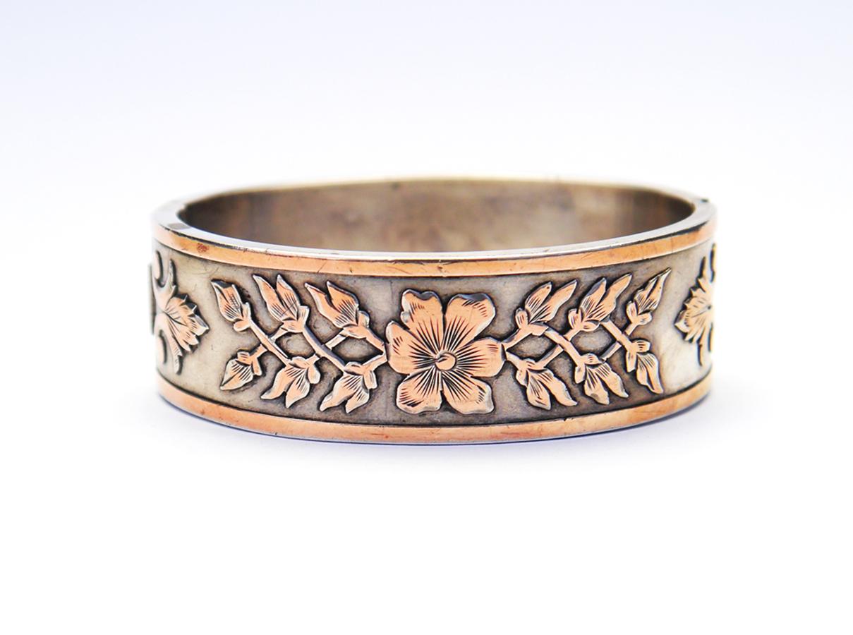 Antique French Sterling Silver Bangle Bracelet in Neoclassical design. Decorated with raised floral ornamentation accented in 14K Rose Gold over Silver.

V- lock and box clasp; inside - peculiar back support plate on the opposite side.

Hallmarked
