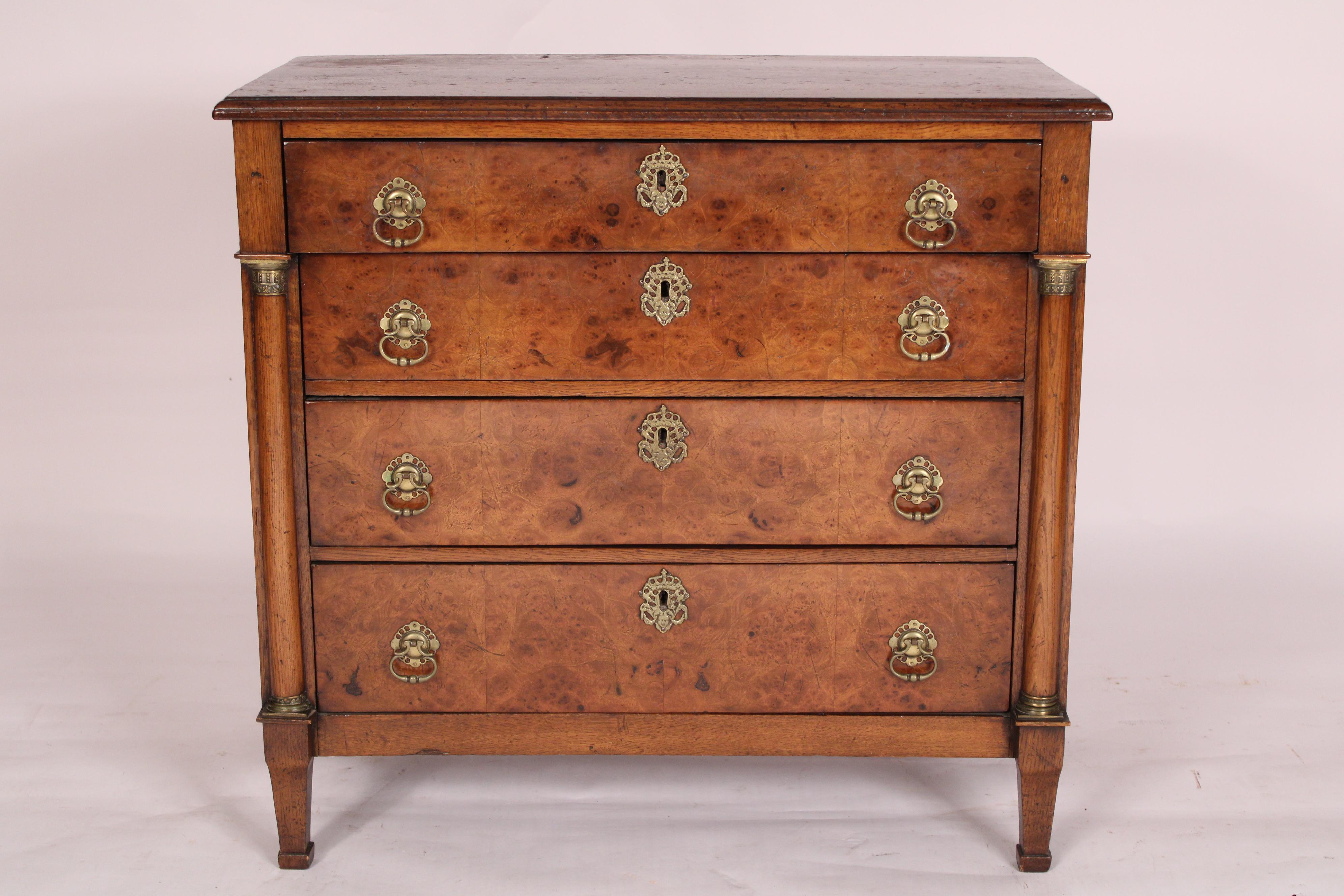 Antique Empire Oak and burl elm chest of drawers, early 19th century. With a 3 board top with molded front and side edges, an overhanging burl elm top drawer and 3 graduated burl elm lower drawers, flanked by columns with brass capitals, resting on