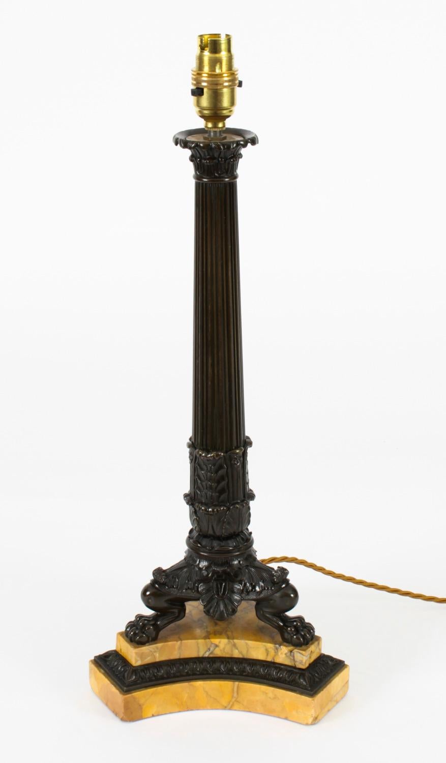 An elegant French Empire bronze and marble table lamp, circa 1820 in date.

The candlestick later converted into a lamp features an ancanthus capital, a fluted tapering column on claw feet raised on a shaped triangular Siena marble and bronze