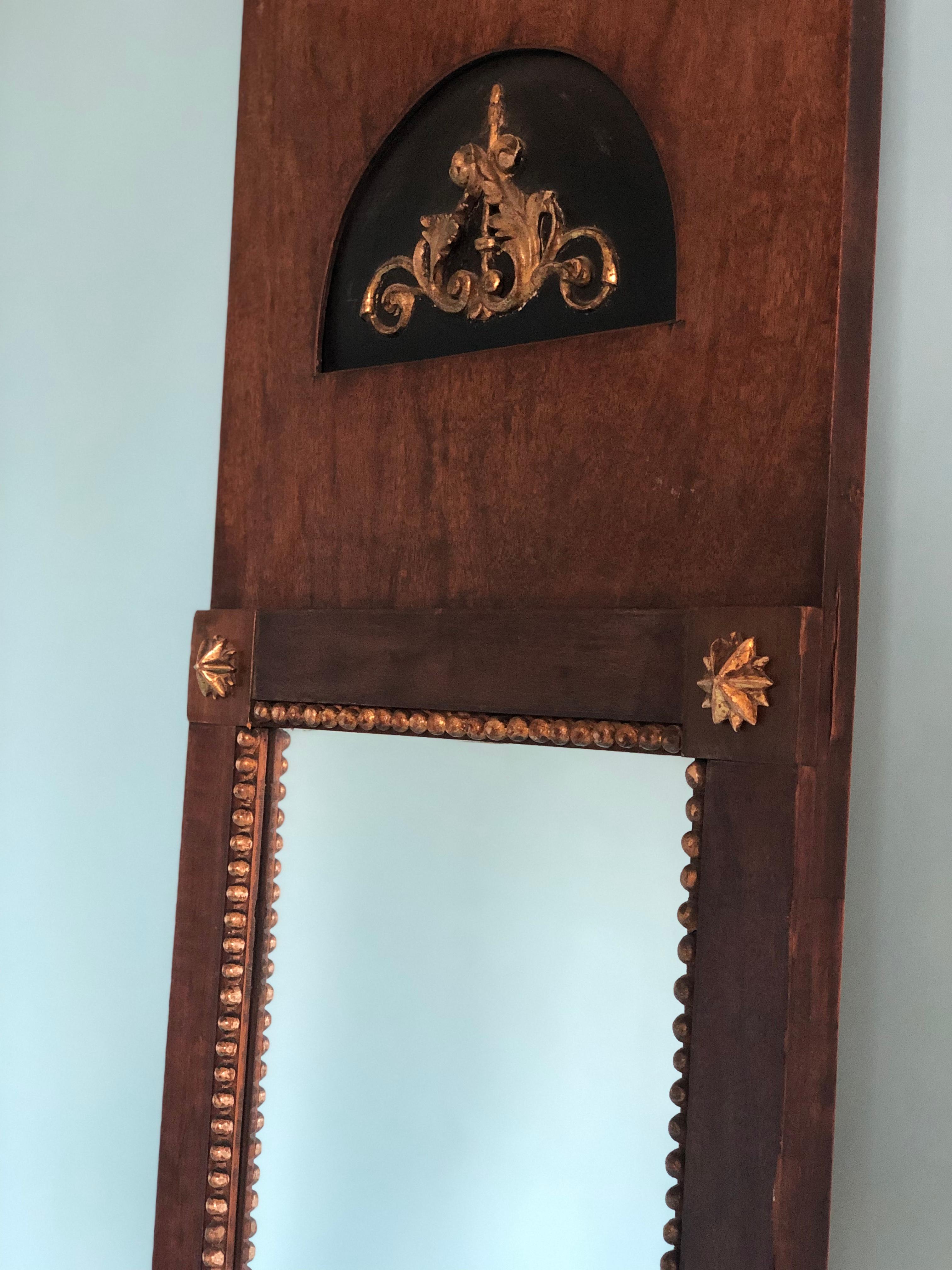 A mahogany and gilded pier mirror from the French Empire, late 19th century. There is a gold-plated pearl rim around the rectangular mirror and a gold-plated flower on the corners. A beautiful ornament at the top.

Beautifully weathered mirror In