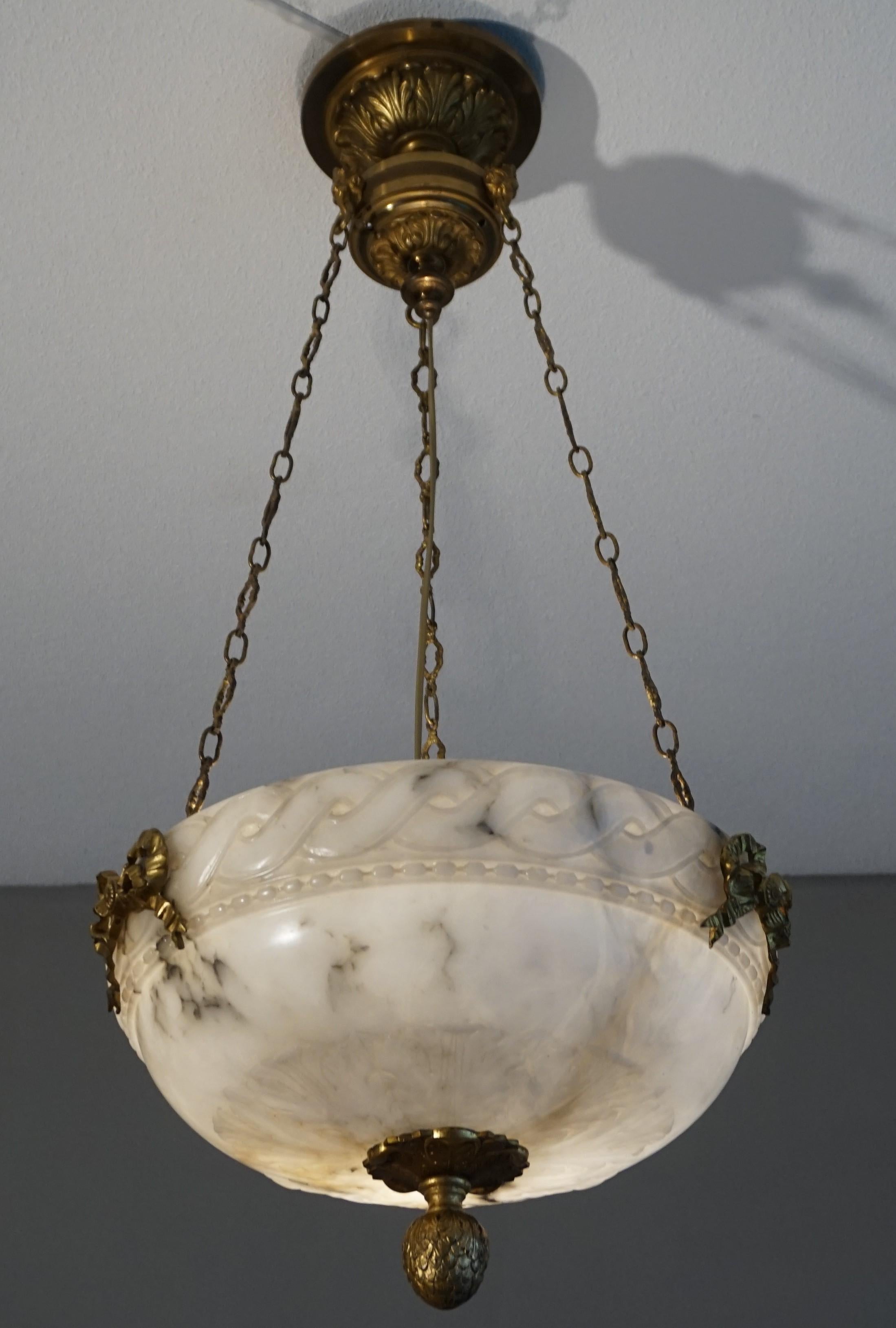 Hand carved alabaster light fixture with stunning bronze decorations, chain and canopy. 

This is one of the oldest alabaster chandeliers that we ever had the priviledge of offering. For us to have found this good size, three light fixture in such