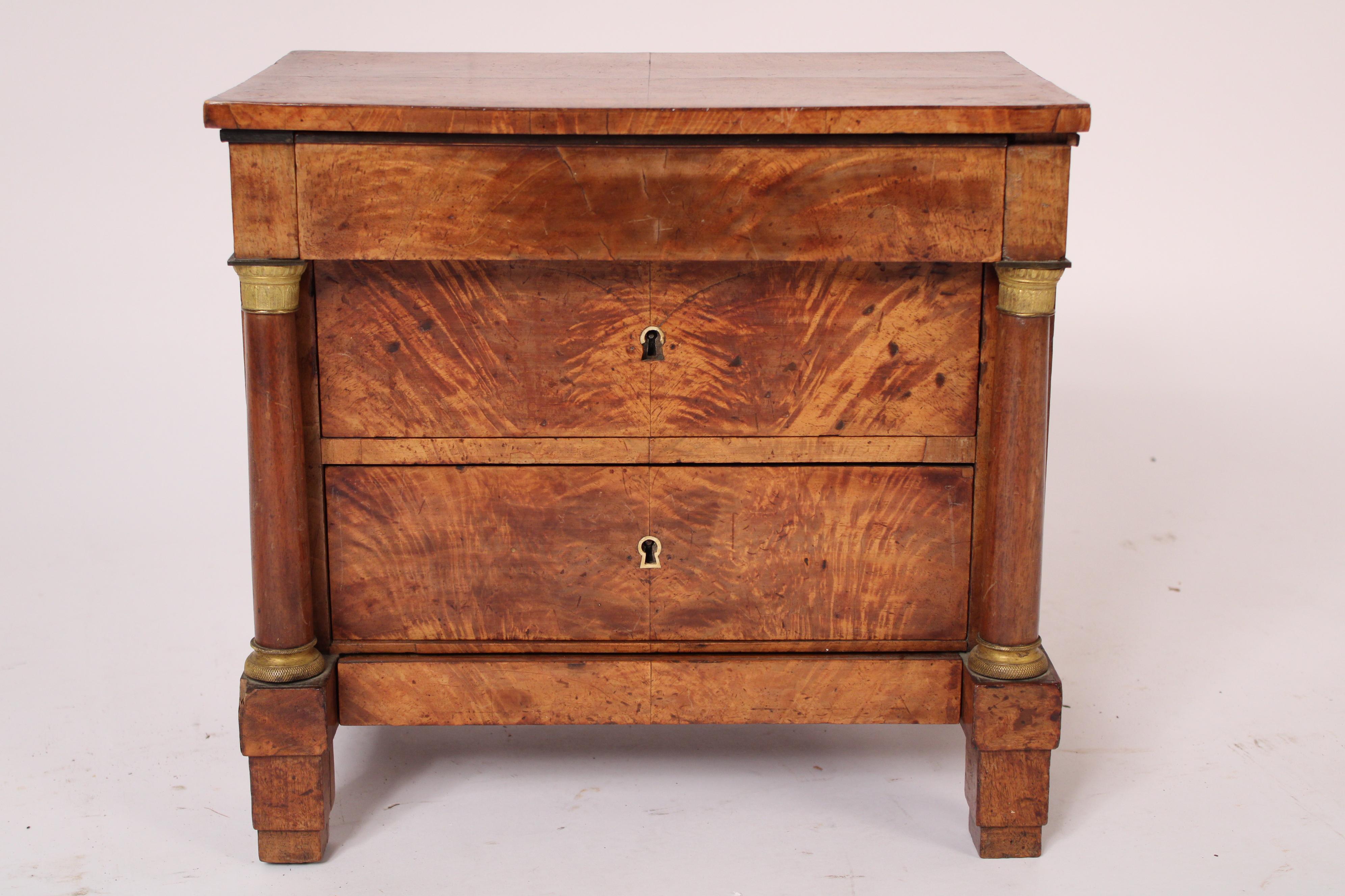 Antique Empire mahogany and birch salesman sample chest of drawers, circa 1820. With a rectangular birch top, a protruding frieze drawer, two larger lower drawers with flame mahogany and an apron drawer, flanked by columns with gilt bronze capitals