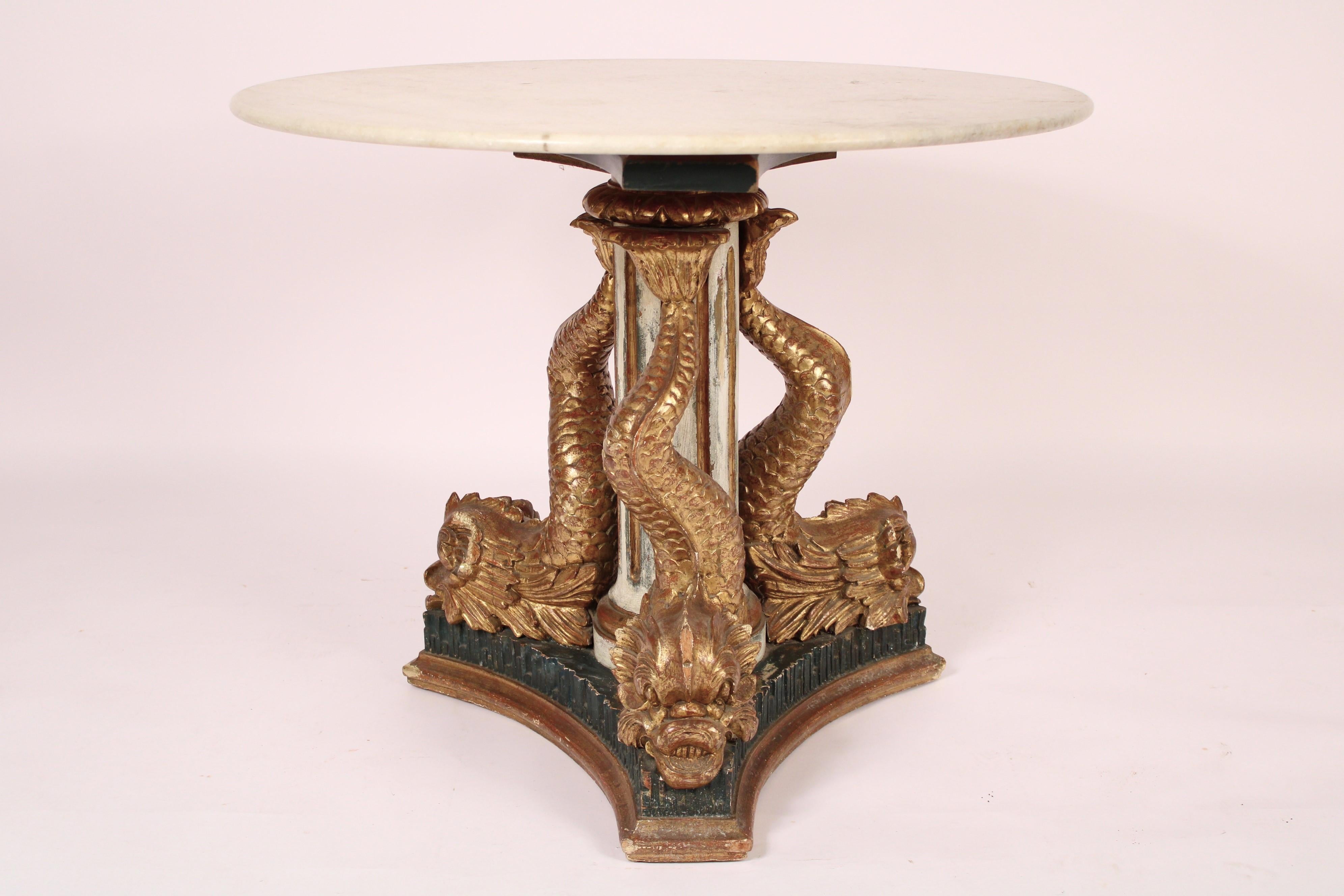 Antique Empire style gilt wood center table with marble top, 19th century. With a round white marble top resting on a painted and fluted column with 3 gilt wood dolphins, resting on a painted and gilded platform base. Could be used either as a