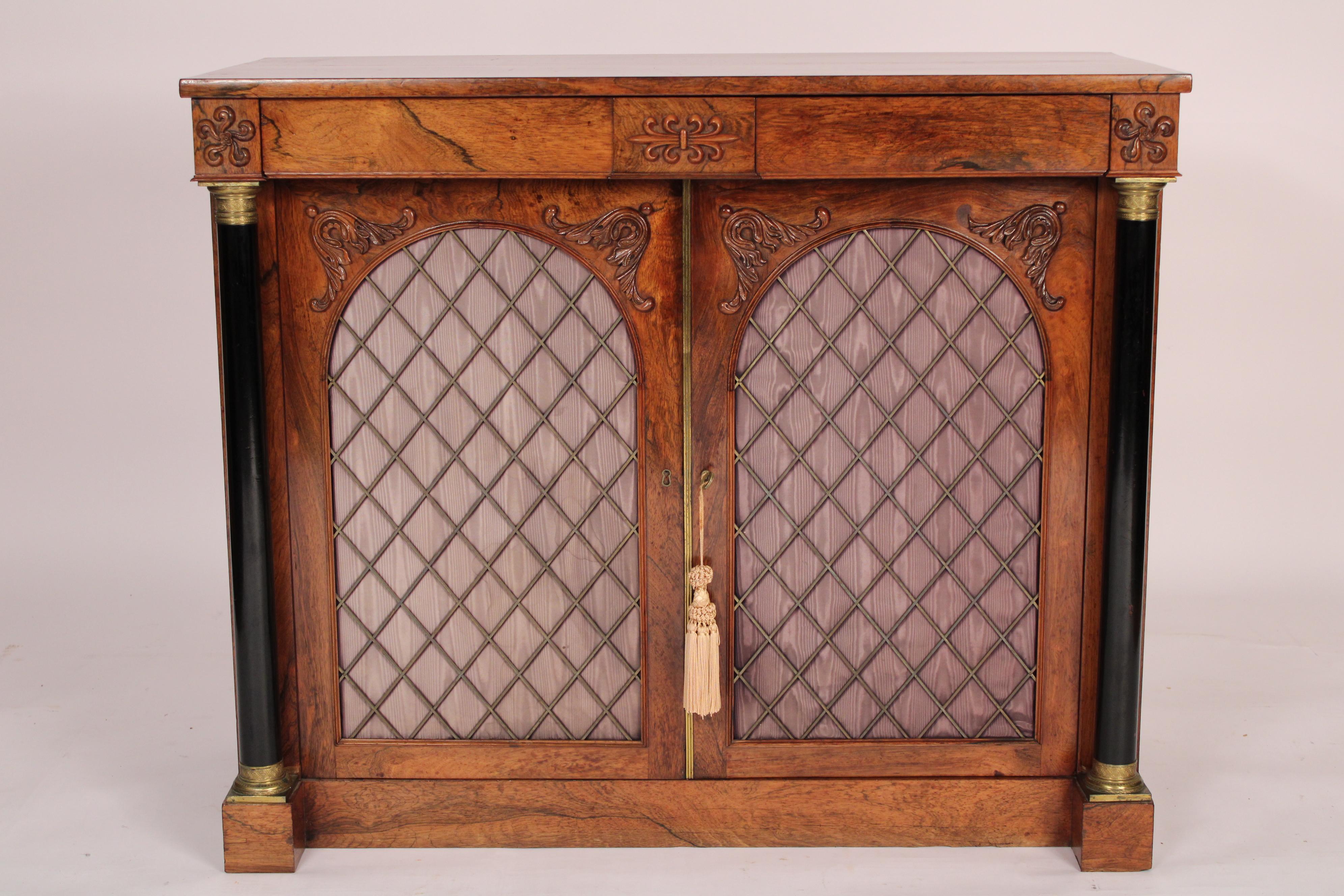Antique Empire style rosewood cabinet, 19th century. With a nicely figured rectangular rosewood top, two frieze drawers, two doors each with arched tops and lozenge shaped grill work backed with moire silk panels, flanked by black lacquer columns