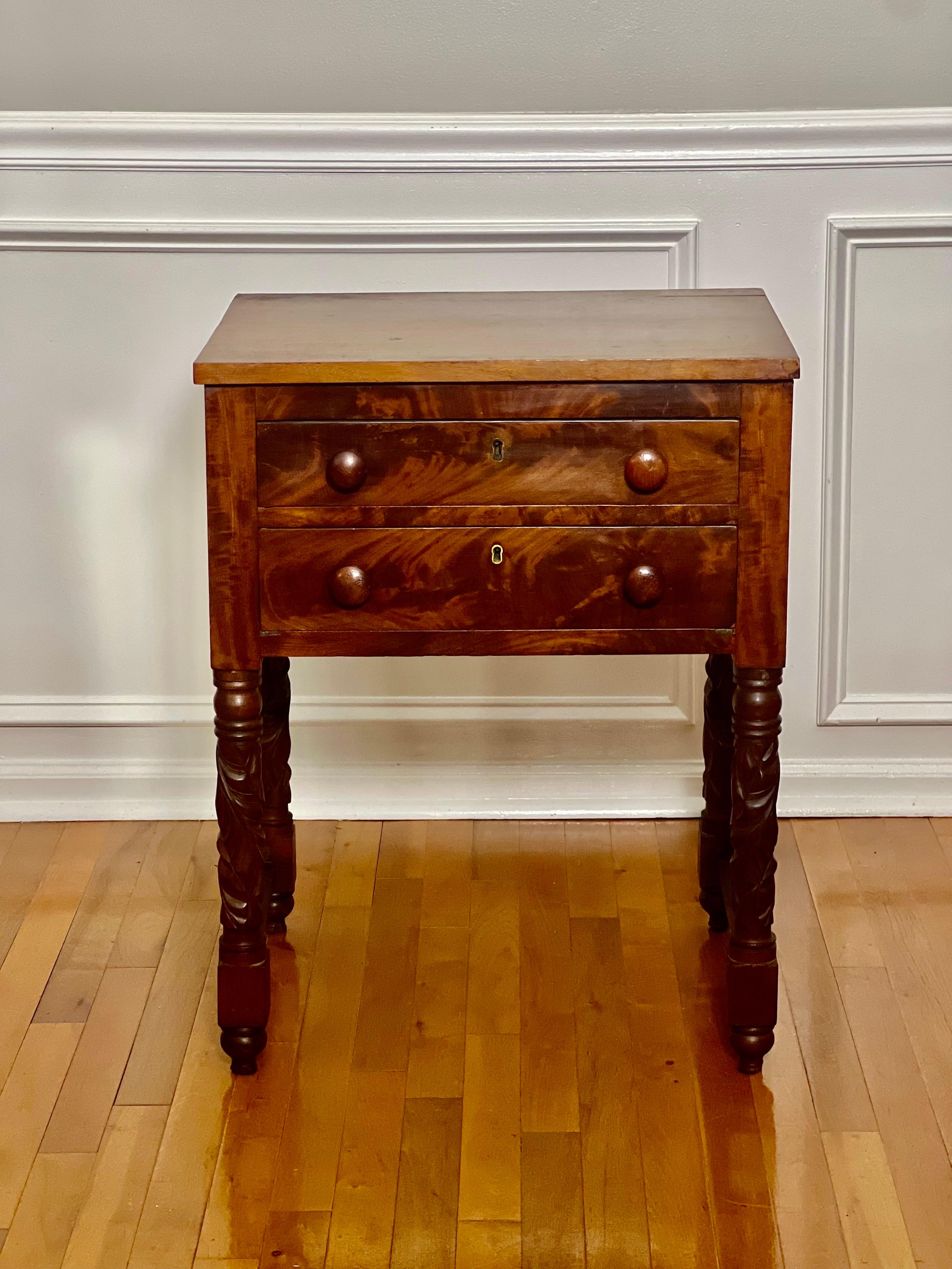 Antiguo atril Imperio del siglo XIX con dos cajones de caoba flameada. Presenta cajones de cola de milano con pomos de madera originales, un respaldo acabado y patas audazmente talladas con diseño de hojas de acanto. Es muy versátil, ya que puede