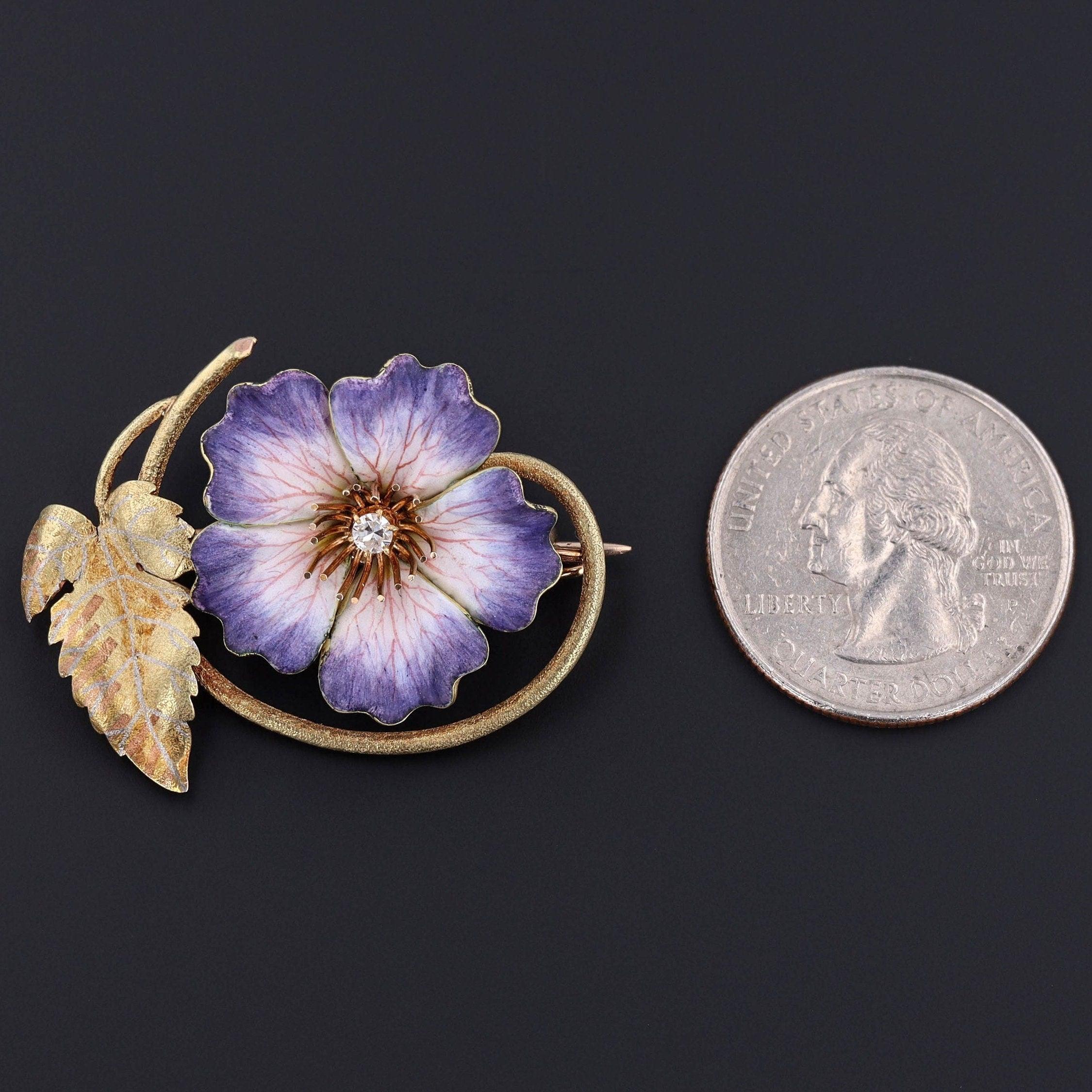 Aggiungi un tocco di bellezza floreale a qualsiasi vestito con questa splendida spilla antica!

La spilla in oro 14k (circa 1890) presenta un fiore in smalto viola e bianco con venature disegnate a mano e un diamante scintillante al centro. 

Il