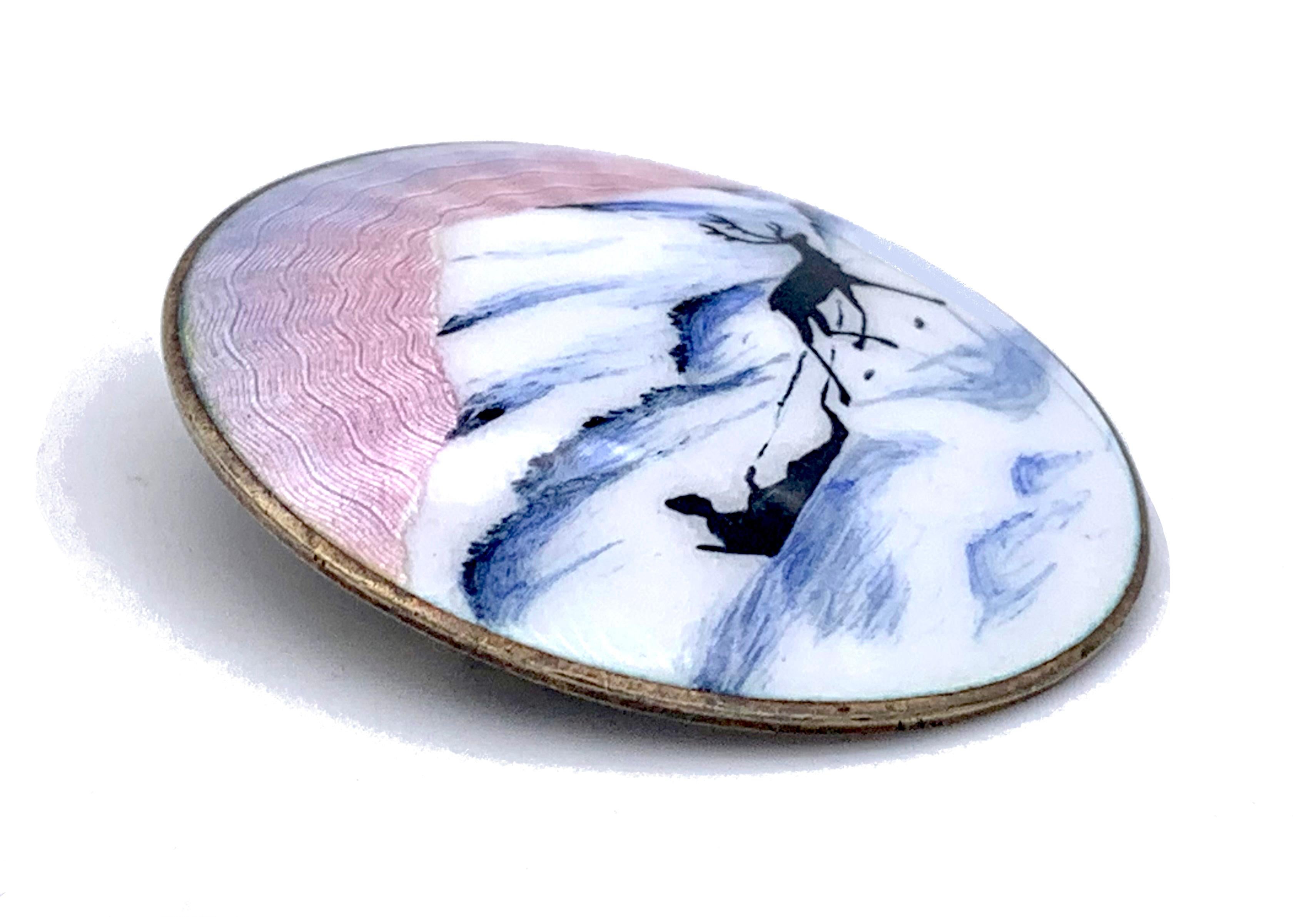 Este precioso broche de plata de ley está pintado con una escena invernal esmaltada. El trabajo de guilloché bajo el esmalte translúcido de tinta púrpura azul pálido representa con una habilidad maravillosa la puesta de sol polar. Delante de una