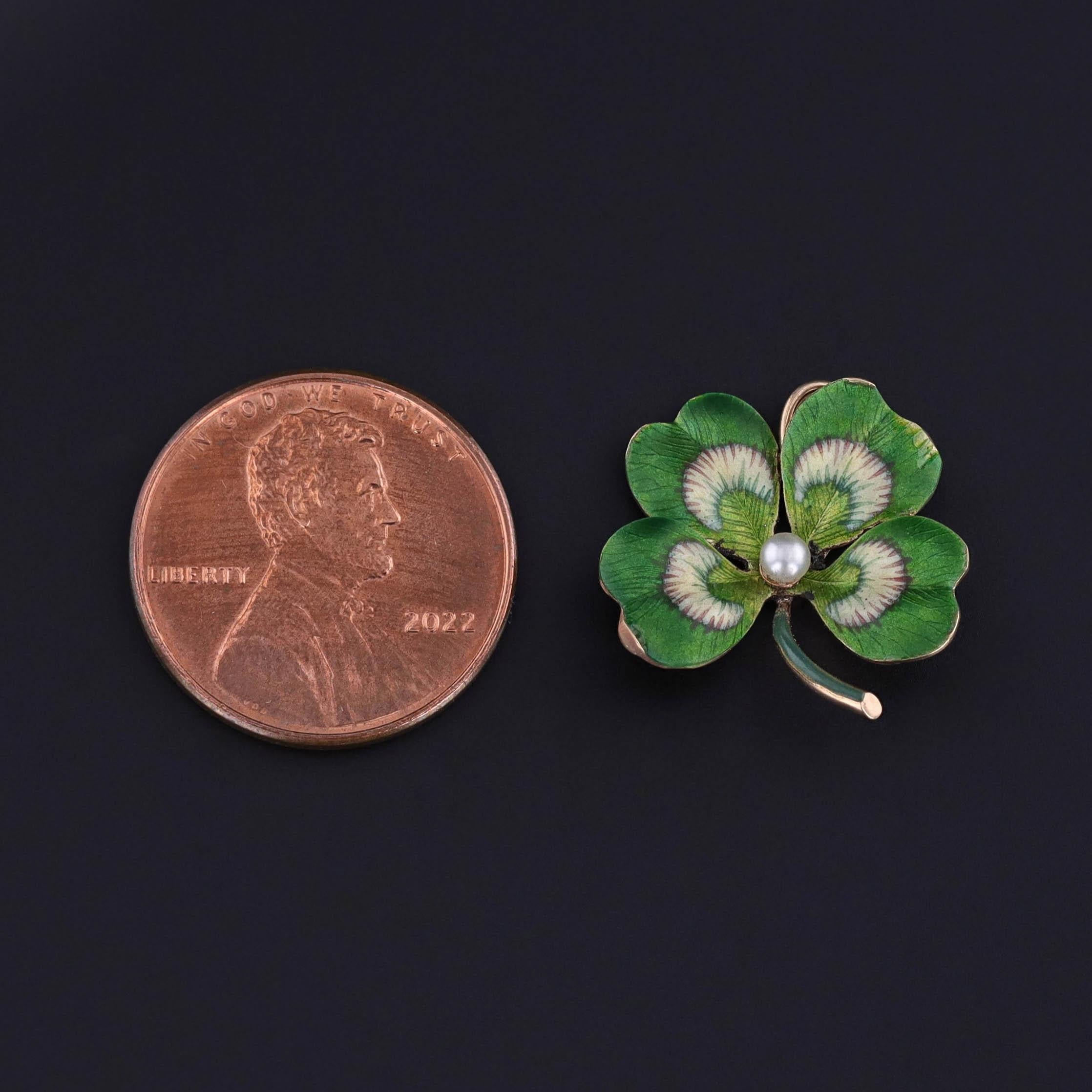 Simbolo affascinante di fortuna e amore, questo pendente antico (circa 1910) presenta un quadrifoglio finemente lavorato in oro 14k, con i petali ornati da un ricco smalto verde e centrati da una perla lucente. La delicata lavorazione dello smalto e