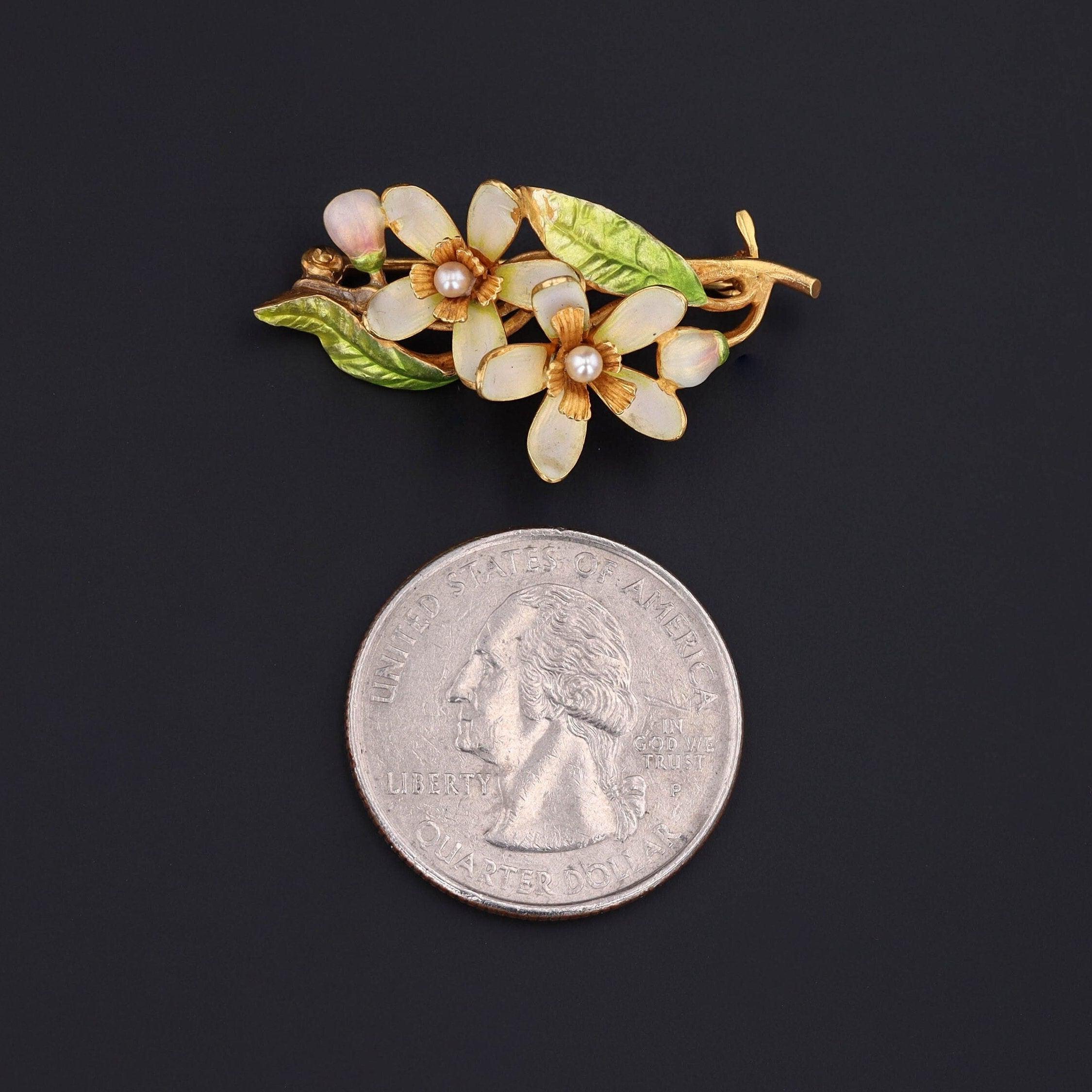 Deux belles fleurs réunies dans cette magnifique broche !

Cette broche ancienne (vers 1910) présente deux fleurs en or 14 carats ornées d'émail jaune pâle et vert avec des accents de perles. La broche porte la marque du célèbre fabricant Krementz &
