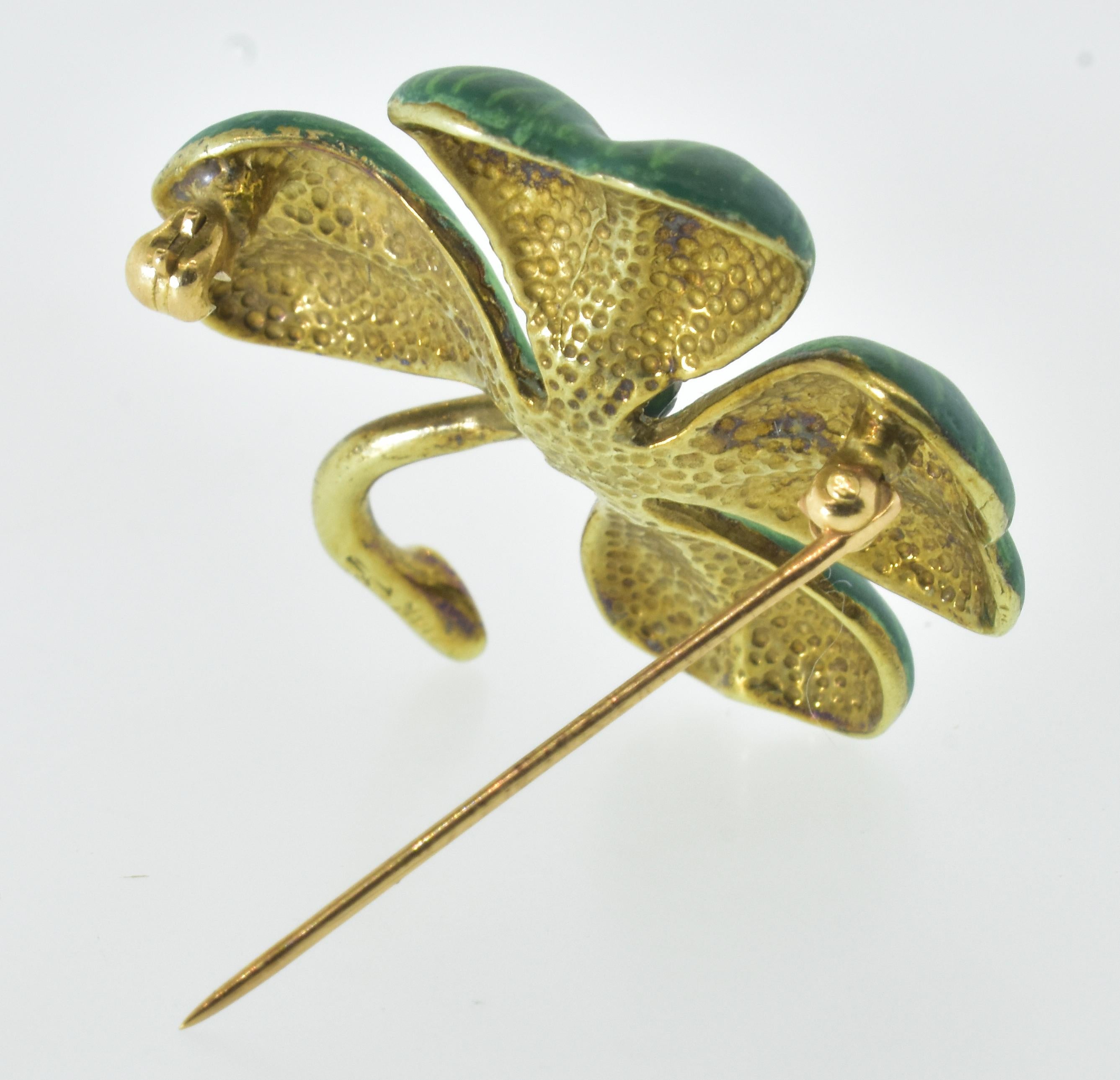 Antique enamel pin with a four leaf clover motif, the leaves are heart shaped.  The pin is 1.25 inches in diameter.  The shaded green enamel is in perfect condition.   The white diamond prong set in the center weighs .10 ct.   The piece is finely