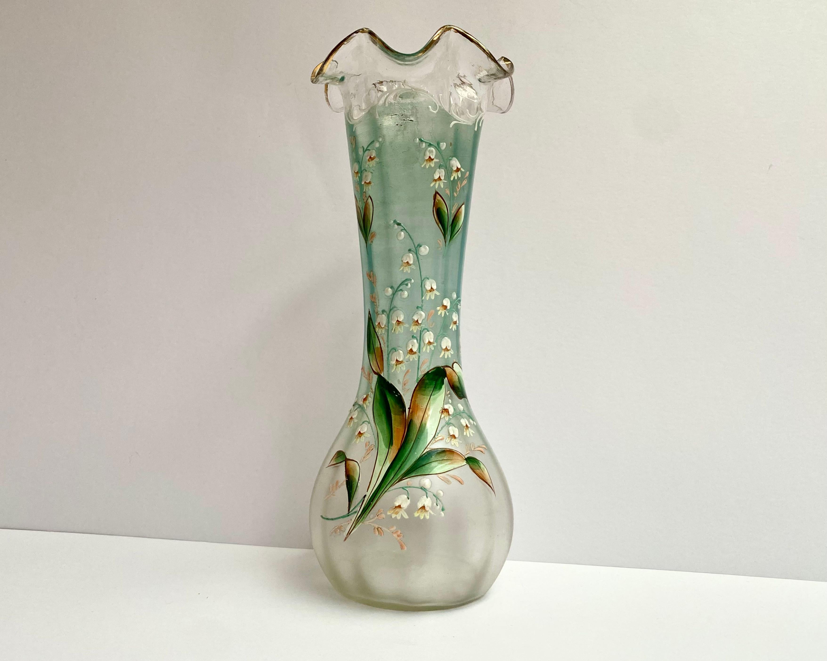 Beautiful antique glass vase with enamel flower details.

The lily flowers on the front are beautifully detailed in white and green. 

The design includes green branches and white pattern. The enamel work is very heavy and gives the flowers a
