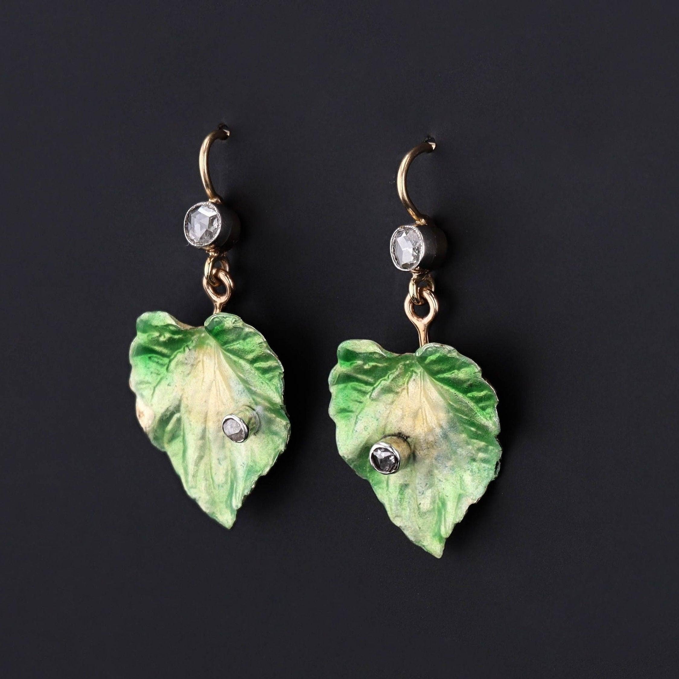 An elegant pair of enamel leaf earrings created from an antique brooch.

These 14k gold earrings shimmer with iridescent green enamel leaves, rose cut diamond accents, and matching rose cut diamond surmounts. The earrings are 14k gold and in very