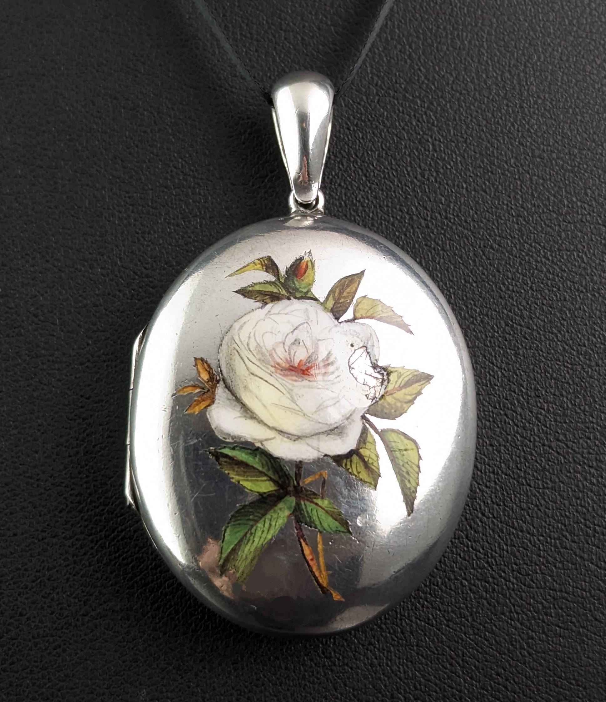 This beautiful antique Victorian sterling silver locket pendant is so pretty and sweet with its attractive enamelled floral design.

It features a meticulously hand painted white rose to the front with leaves and foliate.

It has a large, integral