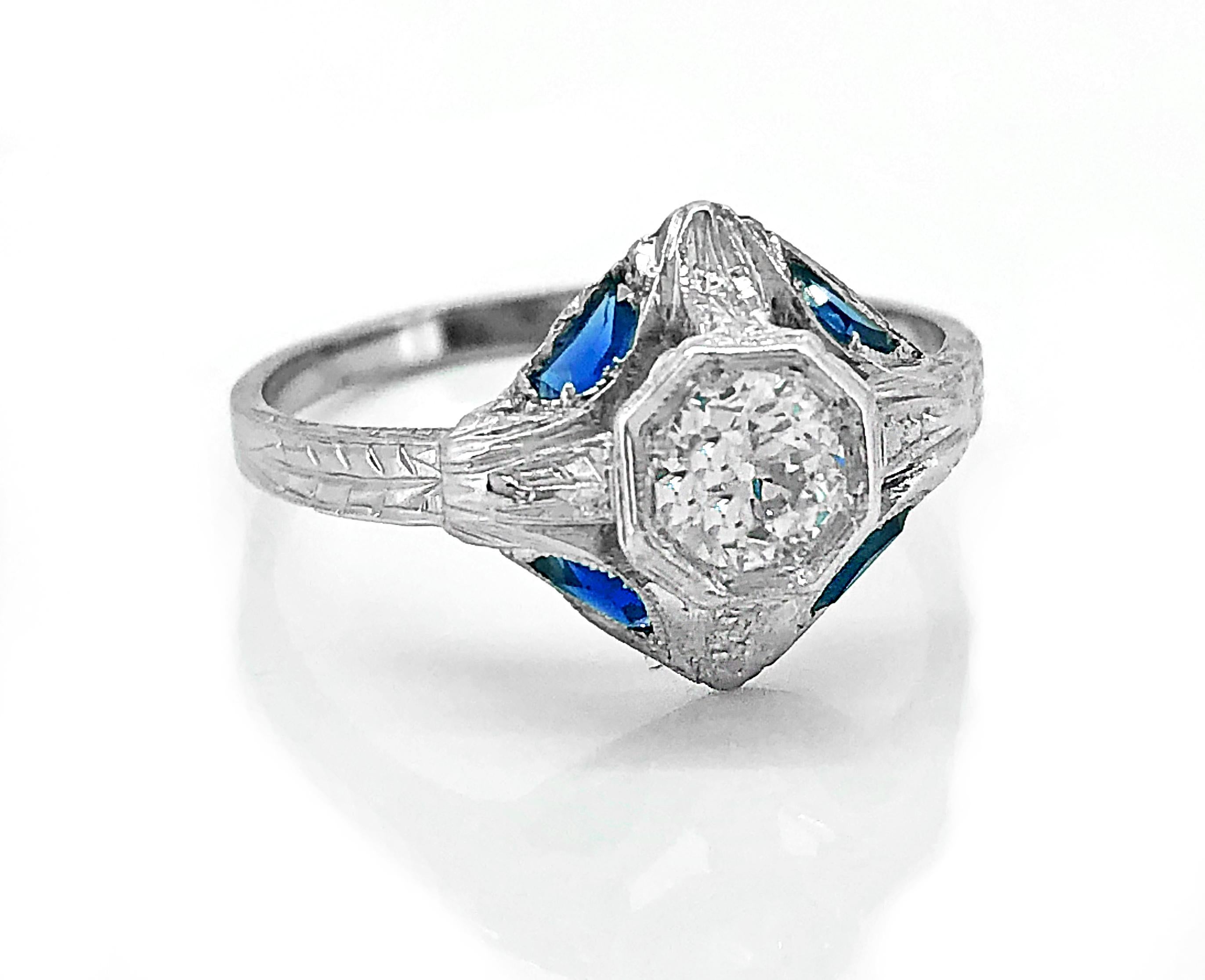 The .43ct. diamond is slightly elevated above the base of the Art Deco Antique engagement ring which is accented with four beautiful lab created sapphires. The sapphires are lab created which was started during the Art Deco time period. The sapphire
