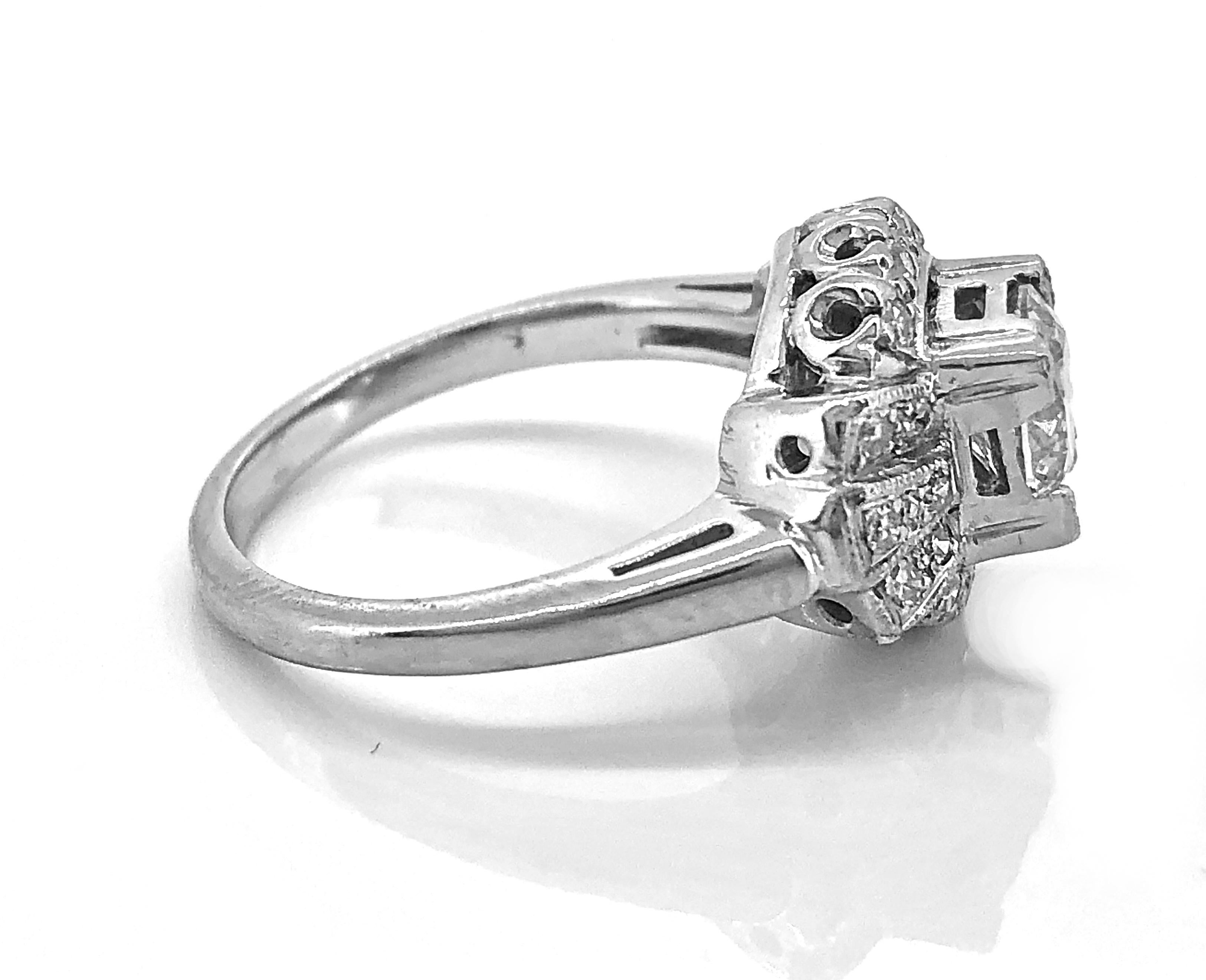 An antique engagement ring crafted in 14K white gold and features a .95ct. apx. European cut center diamond with I1 clarity (100% eye clean) and K color. The center diamond is set with trefoil prongs giving the ring its square look. Additionally,
