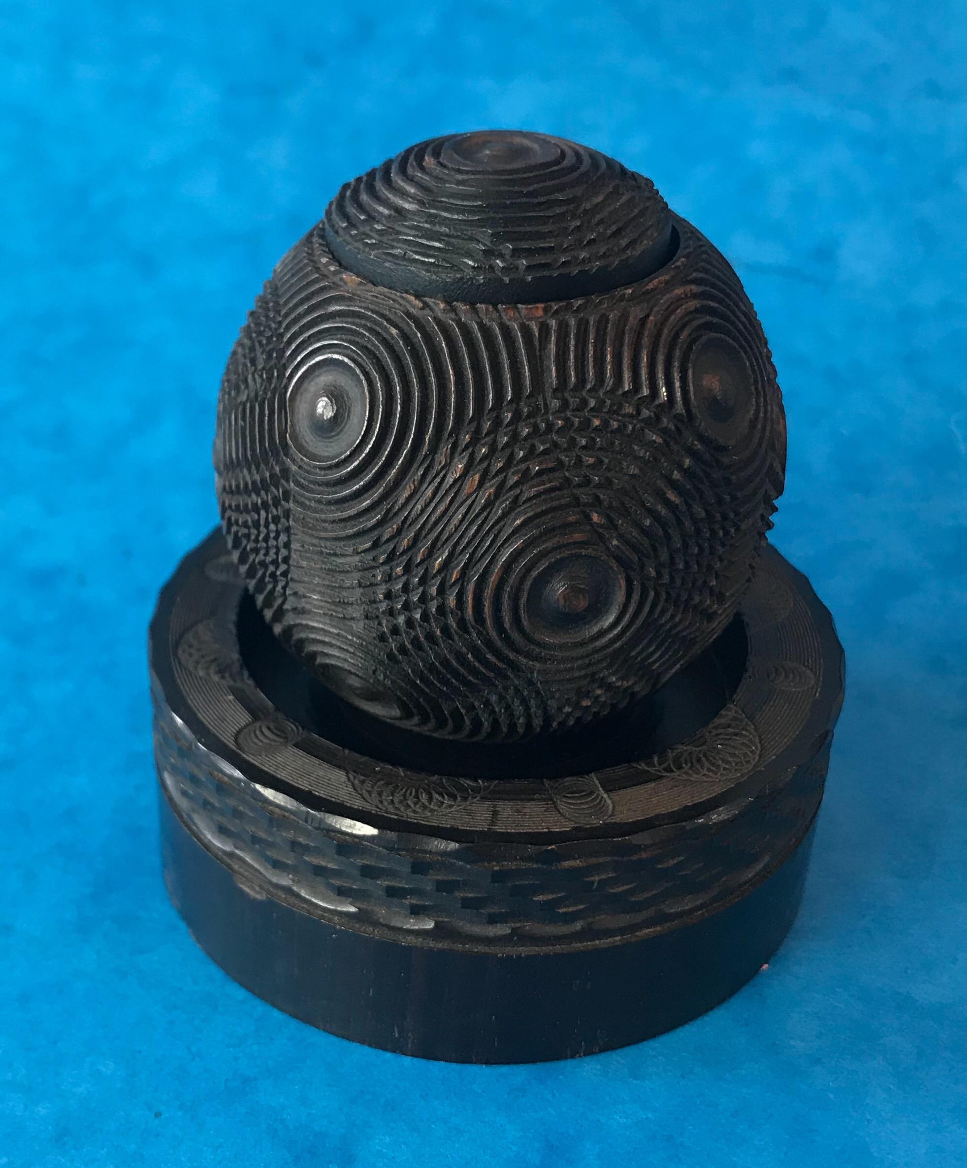 Engine turned puzzle ball box, the puzzle ball sits on a stand, it’s wonderfully patterned ebony, that dates to 1860. It would make a fantastic box to put an engagement ring inside.
The stand measures 8 by 8 and stands 3cm high.