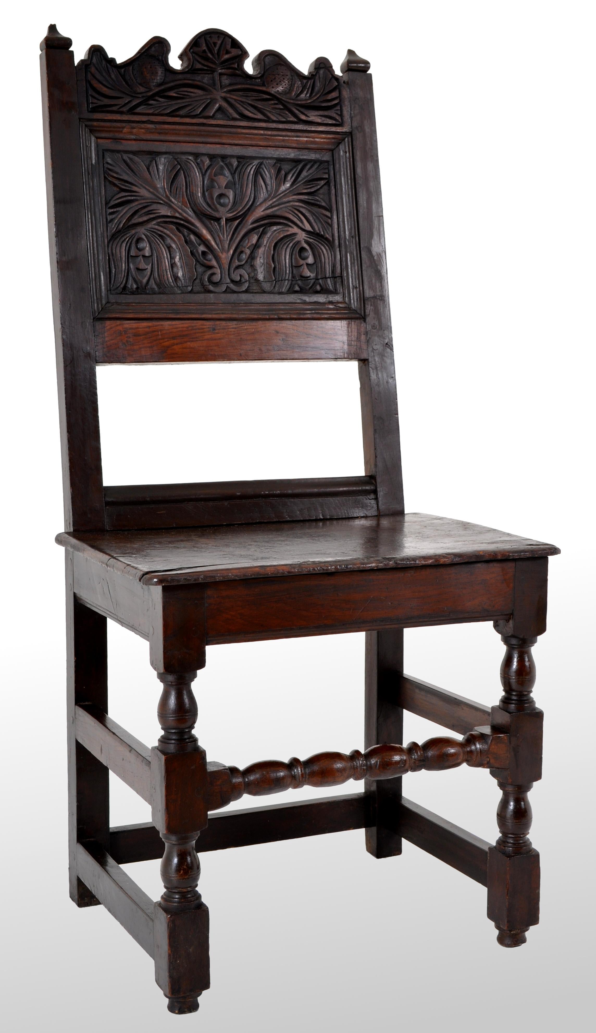 A Jacobean period carved oak chair, circa 1640. The chair having twin finials with a carved panel below with a stylized floral design. The chair having turned legs and a 'bobbin' turned stretcher, the chair of joined and pegged construction.