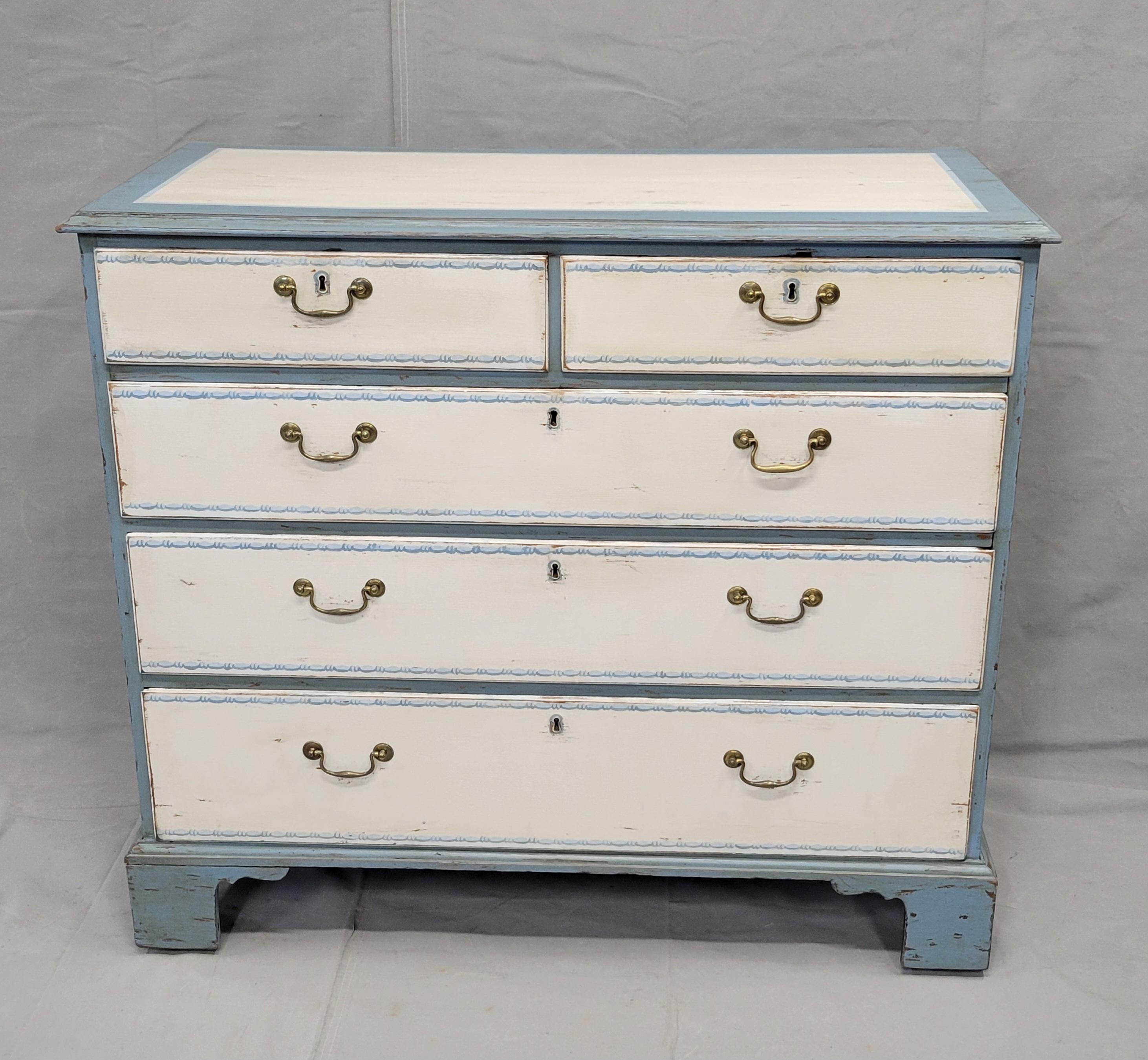 This antique dresser from England dates back to the 1850s and features a beautiful blue and white painted finish on oak wood. A painted, shaded bead stencil design decorates the drawers while distressed blue and white painted panels adorn the top