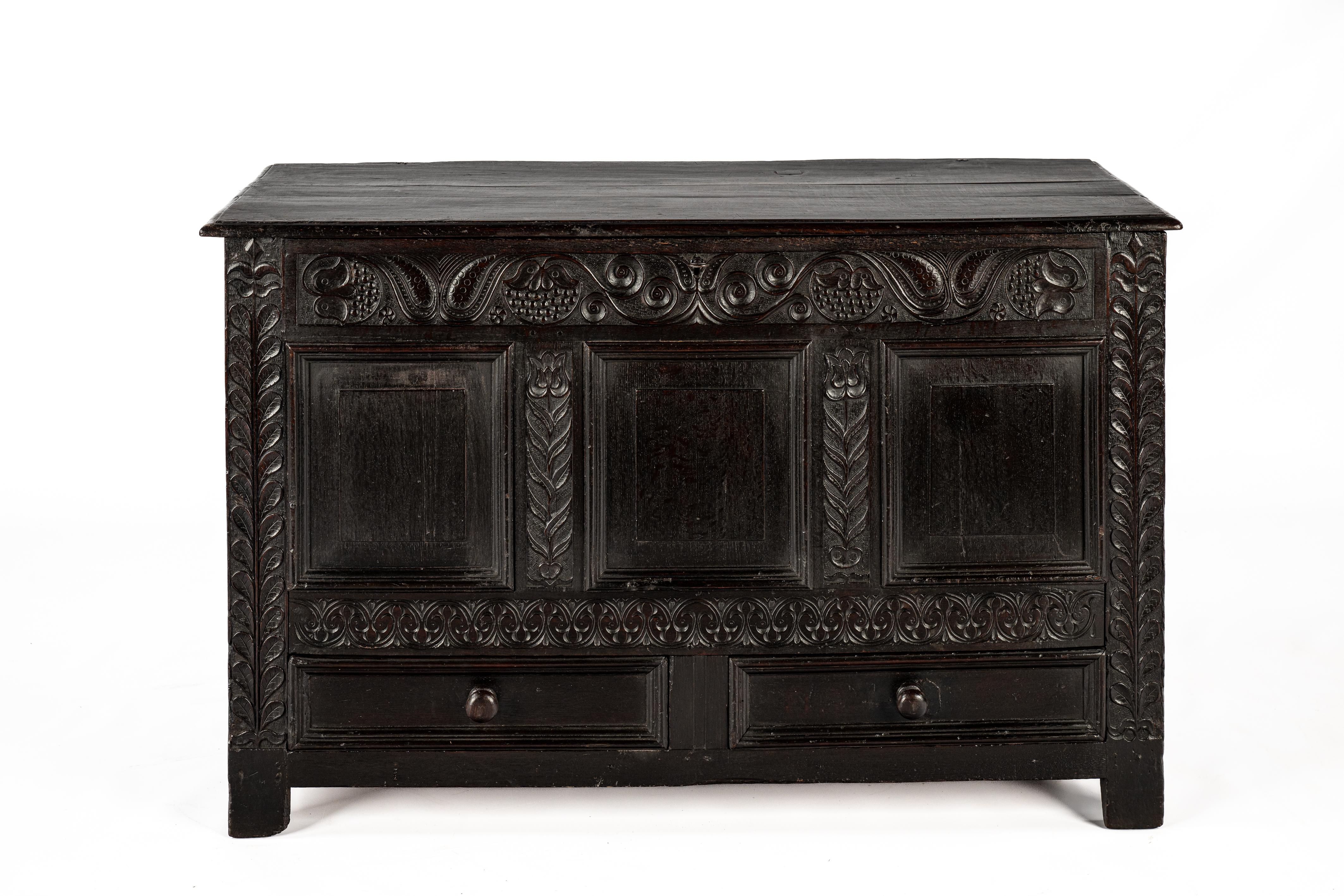 This beautiful antique chest was crafted in England at the end of the 18th century. The chest is entirely made of solid oak wood. Its front features three recessed panels with two drawers underneath. The framework of the chest is richly adorned with