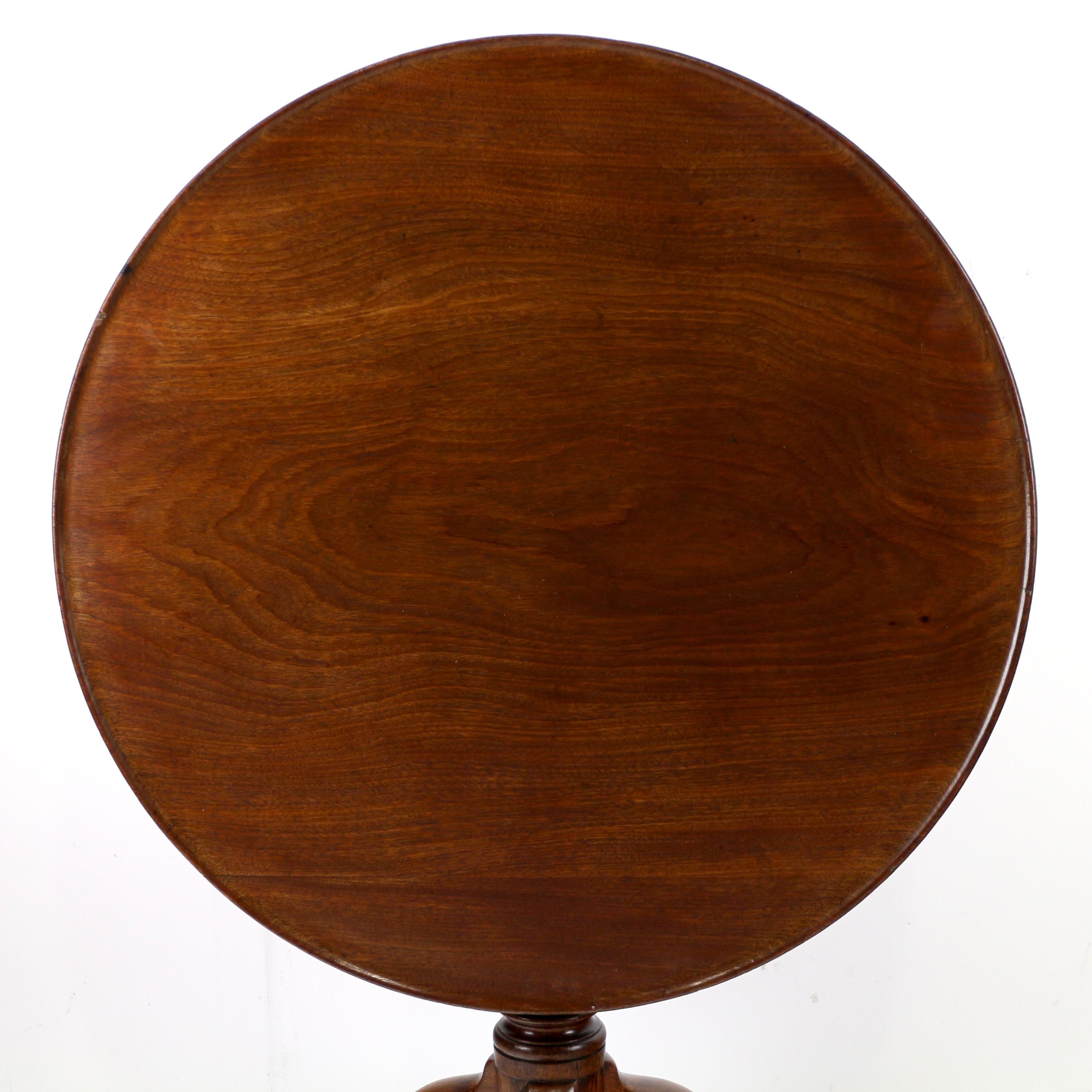 A handsome 18th century early Georgian mahogany tripod tea table with a dish top. It features a solid figured mahogany circular tilt-top with single reeded line to the outer curved edge, with a bird cage mechanism to a turned baluster shaped column