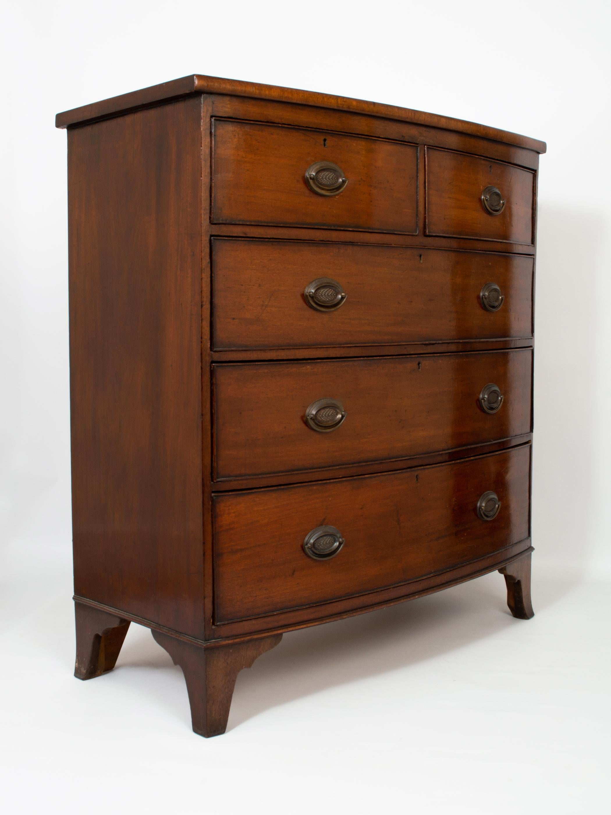 An antique English George III Mahogany bow fronted chest of drawers.
Made in England, dating from C.1800.
Fine quality piece on classic Georgian splayed bracket feet, and oval brass pull handles.
