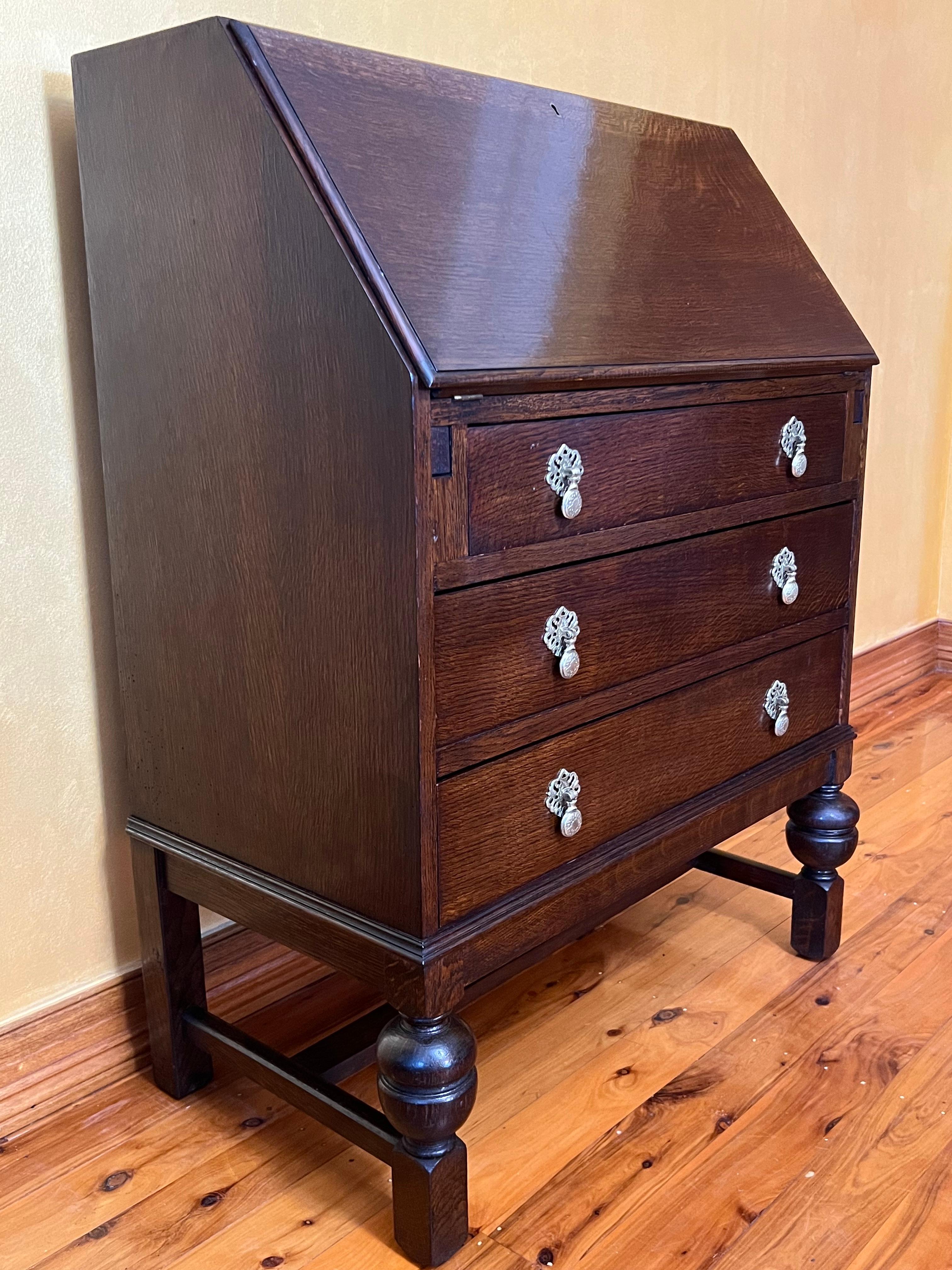 Drop front top with pigeons holes and small drawer, leather insert, three large drawers on bottom, brass fittings. there is not key to top. 

circa: 1920s

Material: Oak

Country of Origin: English

Measurements: 110cm high, 74cm length,