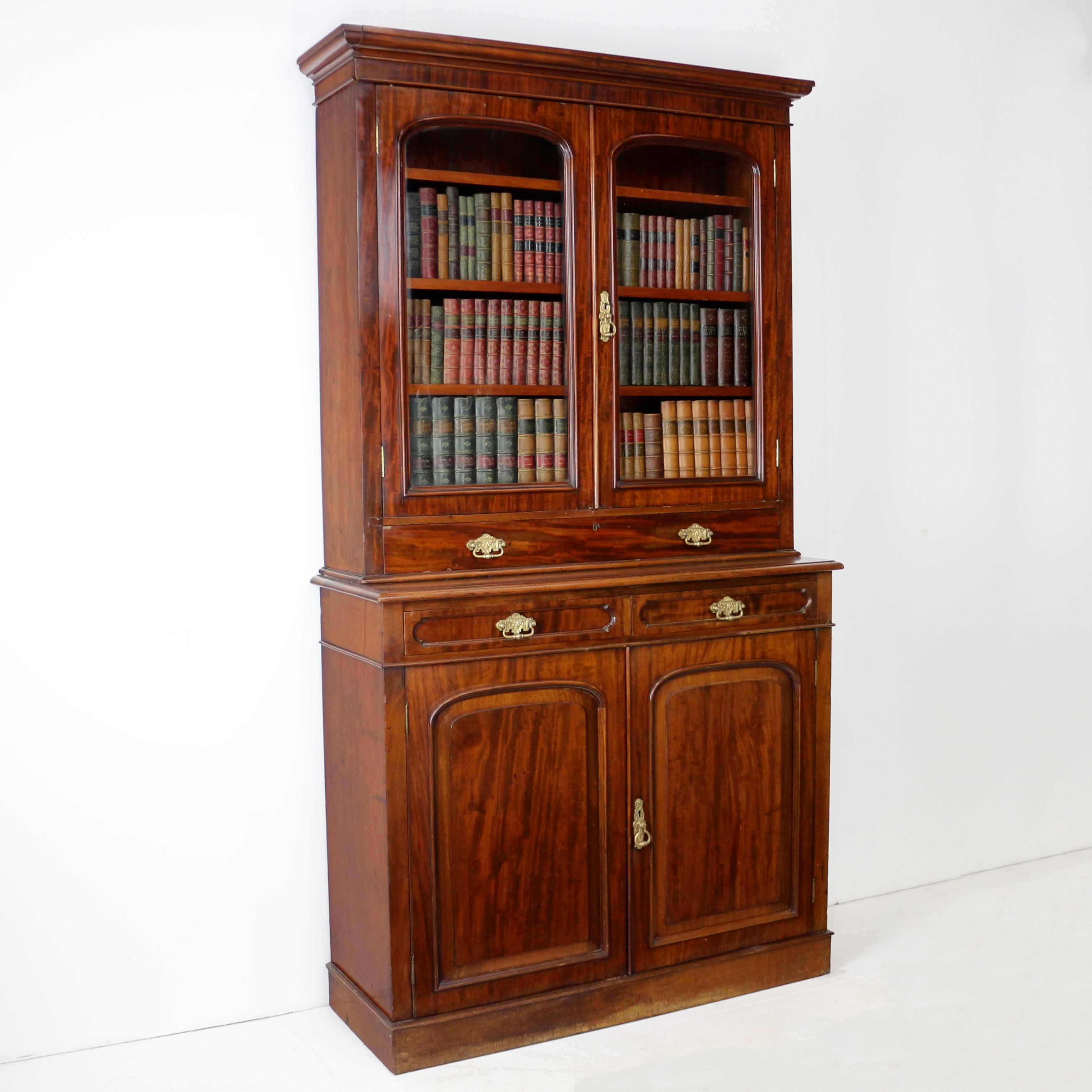 Una bella e insolita libreria/armadio a due ante in mogano di epoca vittoriana risalente al 1850 circa.  La parte superiore presenta una cornice rettangolare modellata sopra due porte vetrate ad arco e un cassetto lungo, la superficie di base
