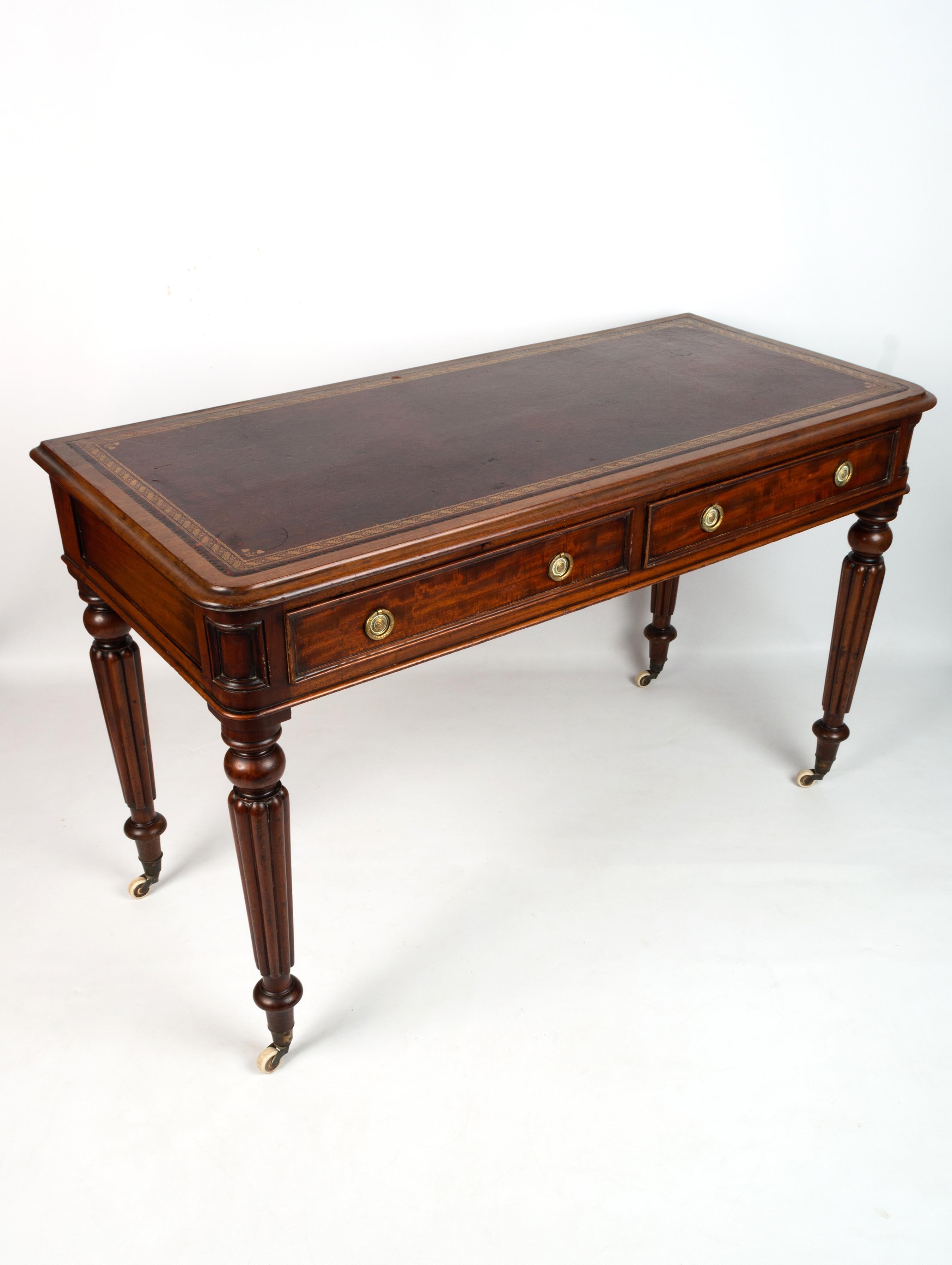 Antique English 19th century Regency mahogany writing desk.

With a tooled leather inset top surface and rounded edges over two long brass pull drawers, raised on reeded tapered legs and brass casters.

In excellent condition commensurate with