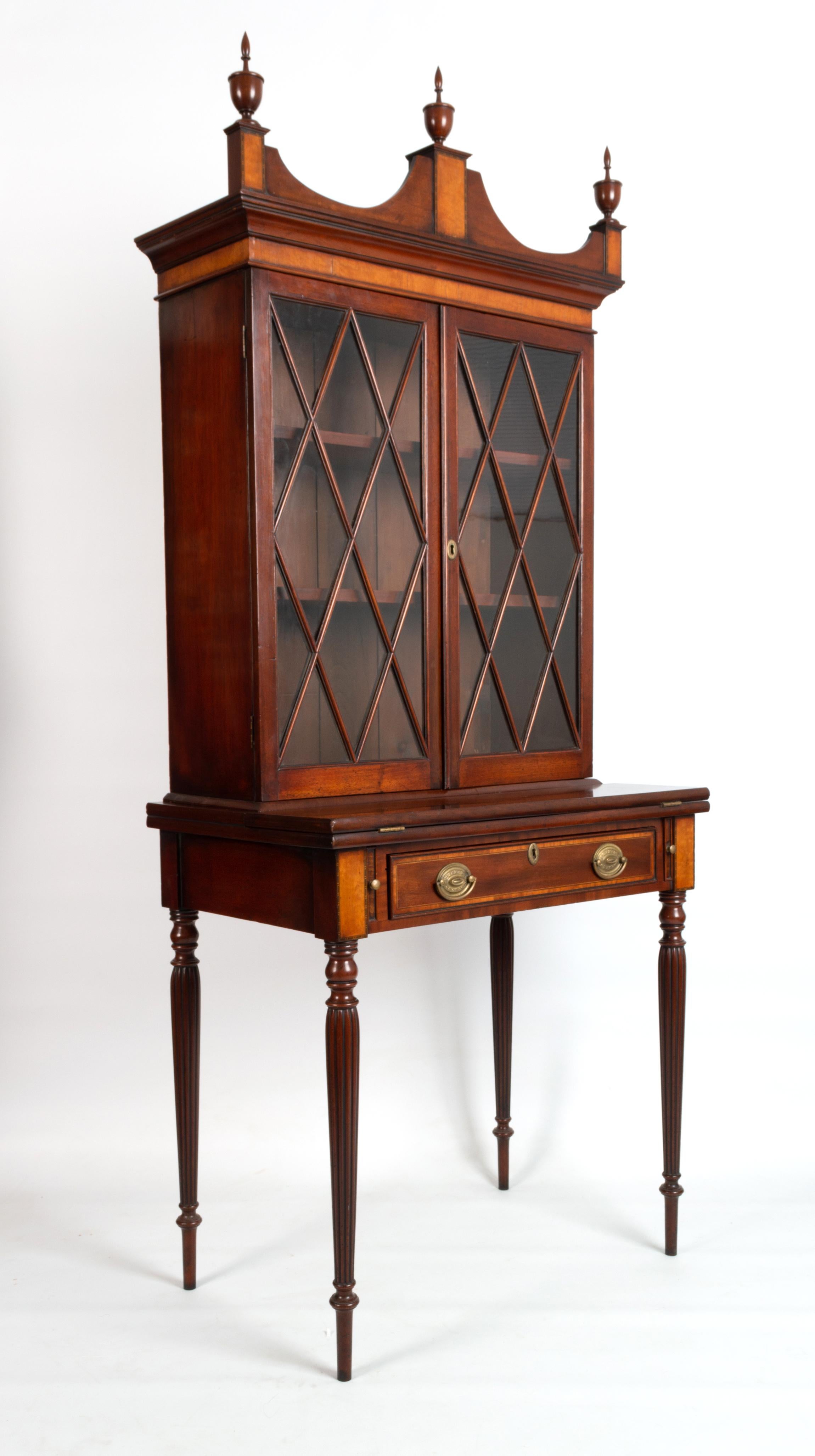 Antique English 19th century Sheraton revival mahogany display cabinet on stand.

A 19th century mahogany display cabinet on stand, the upper section with astragal glazed doors on a table base with fold out writing surface. Standing on turned