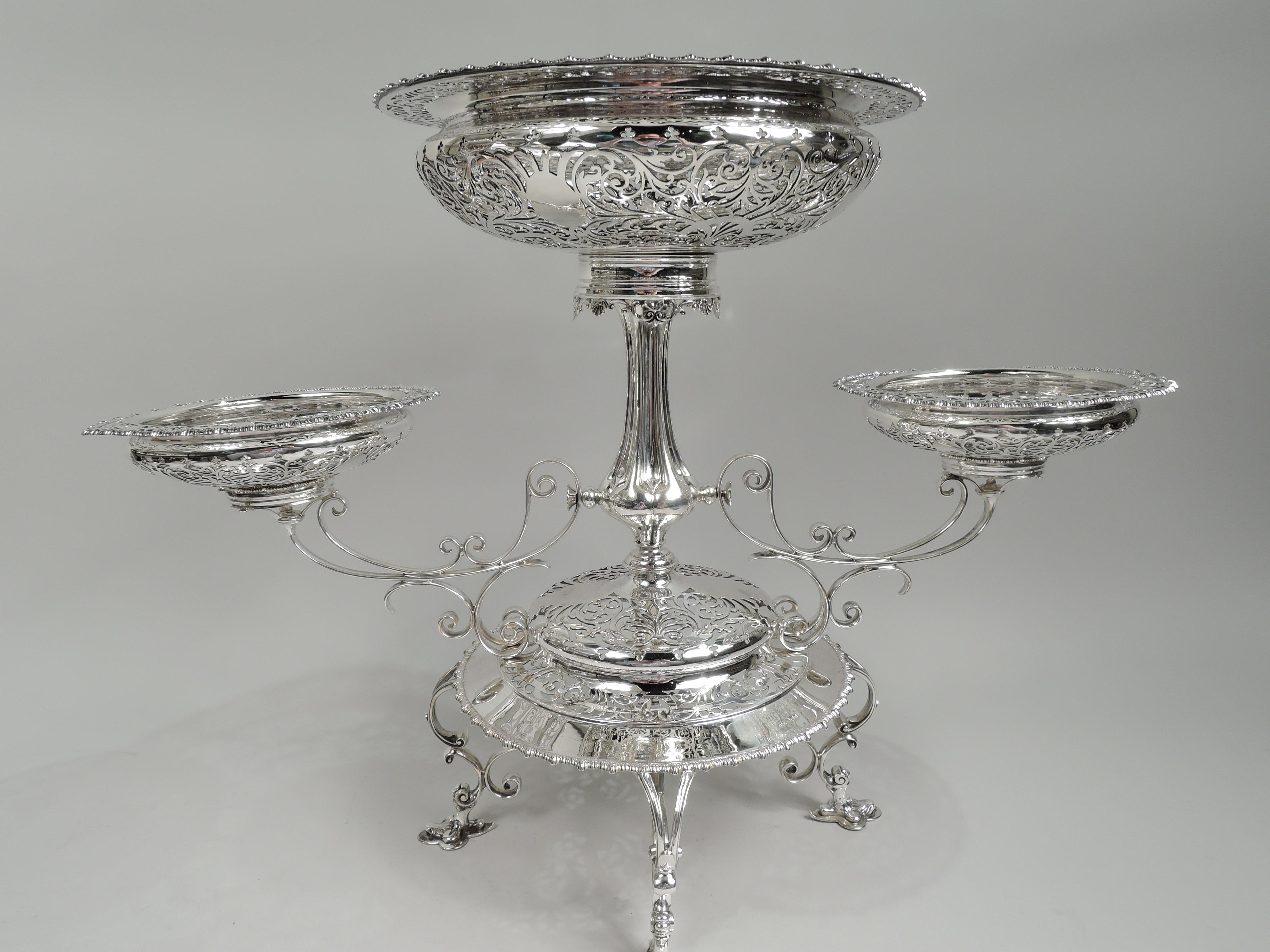 Epergne eduardiana Art Nouveau de plata de ley. Fabricado por James Dixon & Sons en Sheffield en 1905. Gran cesta redonda y poco profunda en montura redonda con delantal de concha y roleos que remata un balaustre estriado y nudoso sobre una base