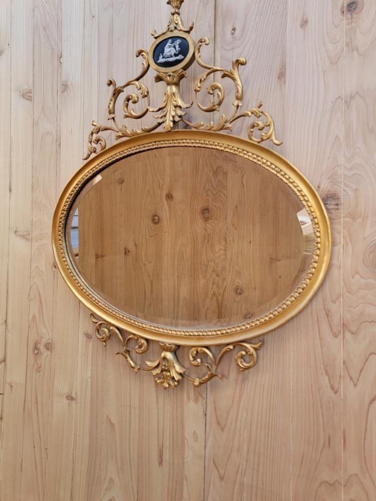Antique English Adam Wedgwood style gold gilded oval wall mirror

An exceptional Adam Wedgwood style black cameo of a mother and child set within a surround of foliate scrolling wire work. The horizontal cameo makes this most unusual. The