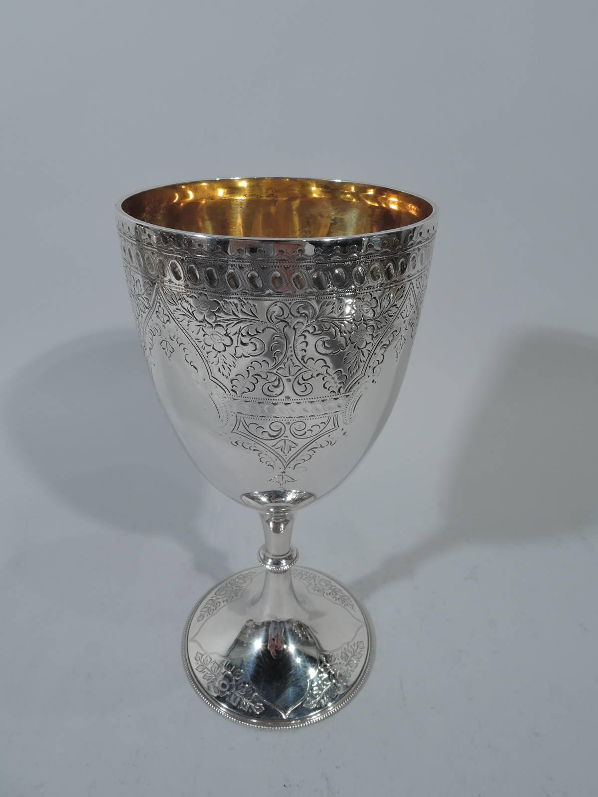 Victorian sterling silver goblet. Made by Walker & Hall in Sheffield in 1897. Ovoid bowl on knopped stamp on raised foot. Dense and stylized scrolls and flowers forming exotic multifoil frames (vacant). Beading. Bowl interior has strong yellow