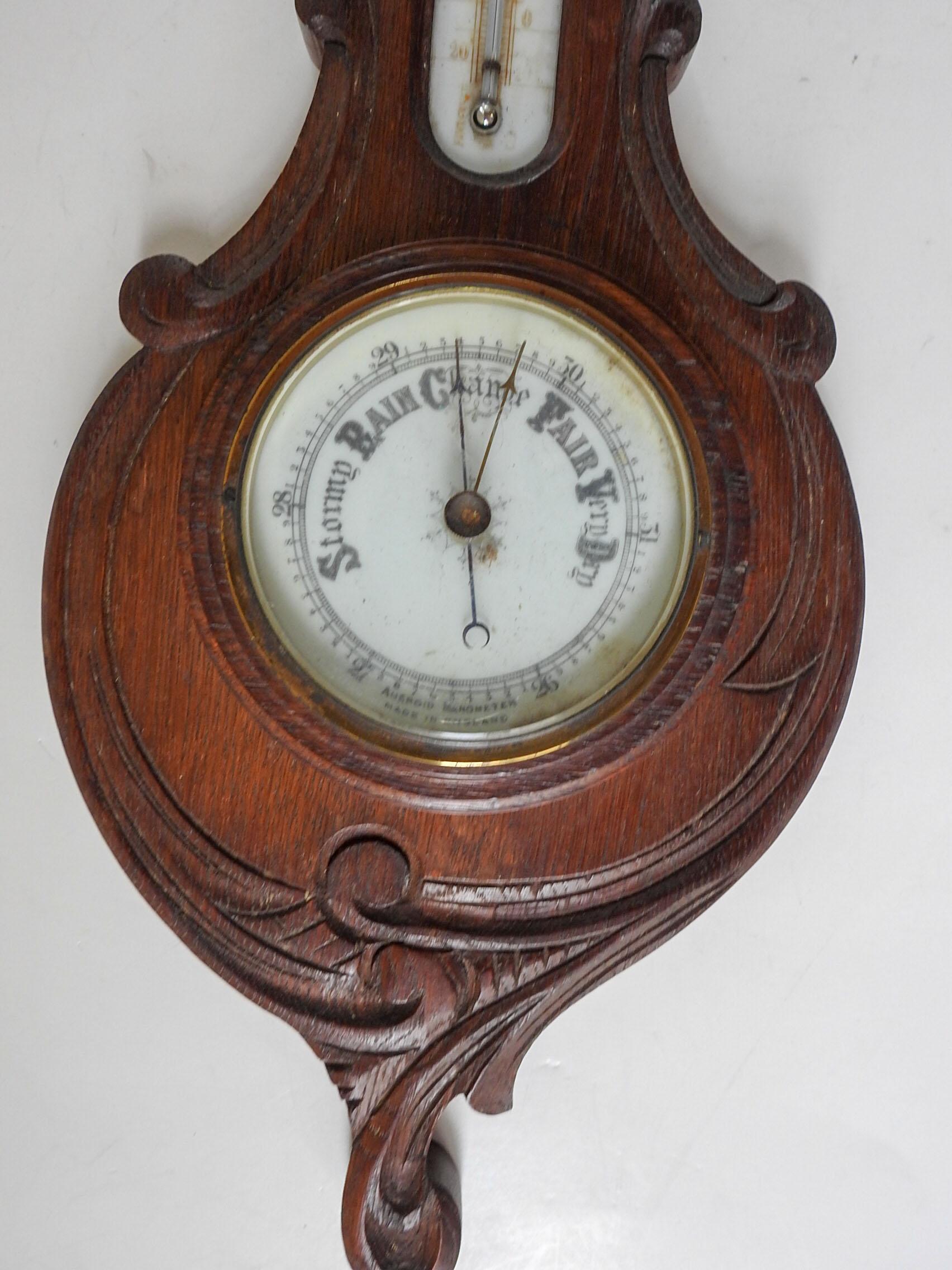 Antique circa 1900 aneroid barometer and thermometer.  Made in England, carved oak case, banjo shaped with white porcelain dials, beveled glass cover, on barometer. Thermometer works, not sure about barometer, but dial does change position.  Wear to
